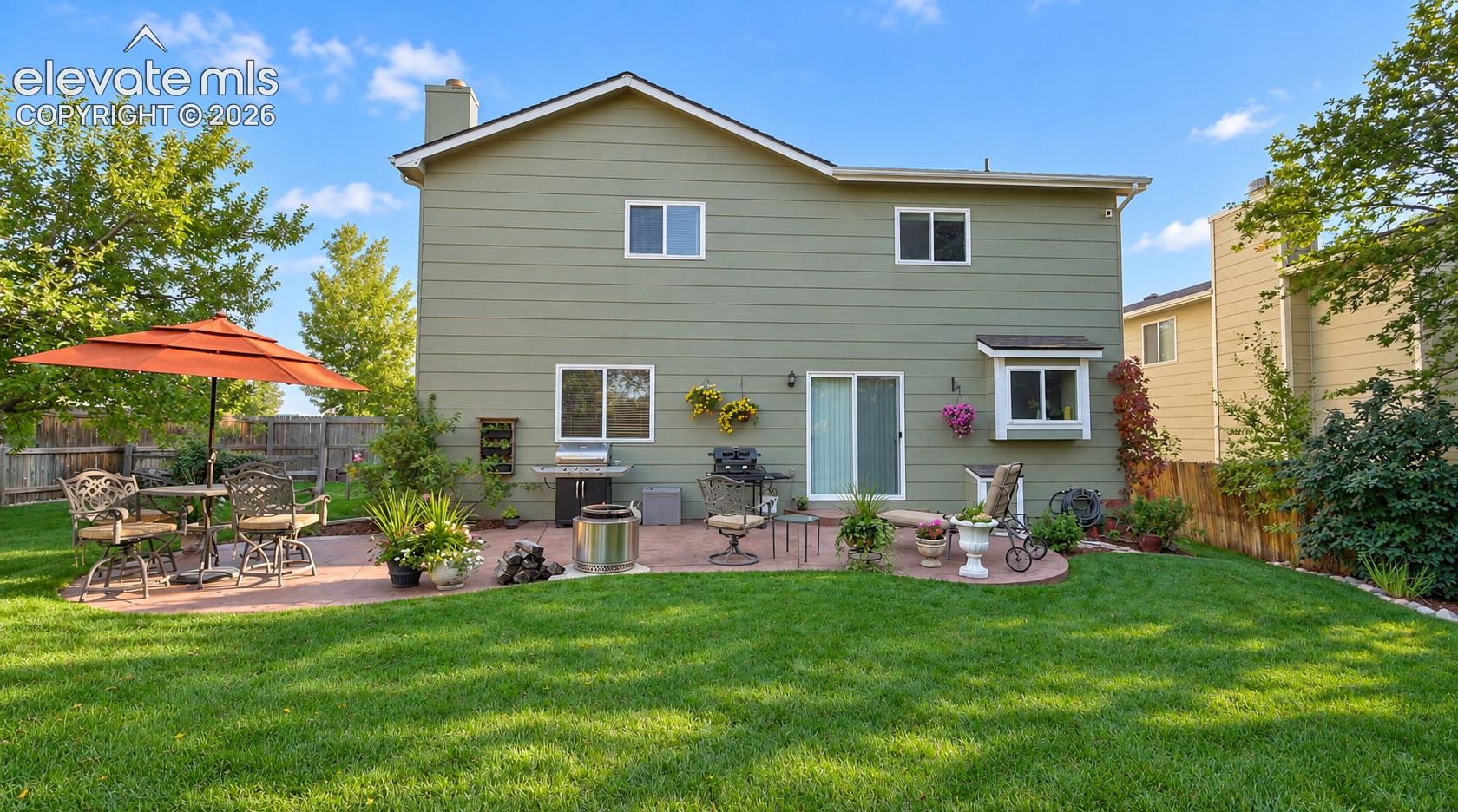 Fenced backyard in a park like setting with concrete patio for outdoor dining and relaxation, mature trees for privacy and shade, tranquil rock water pond with waterfall, and flagstone seating area amongst the trees.