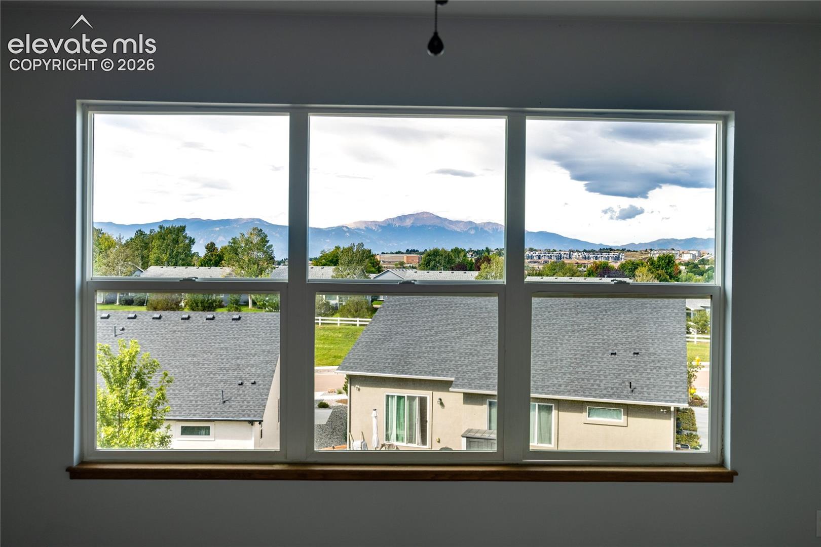 Large multi-pane window with a wood-finish sill, showcasing a mountain backdrop