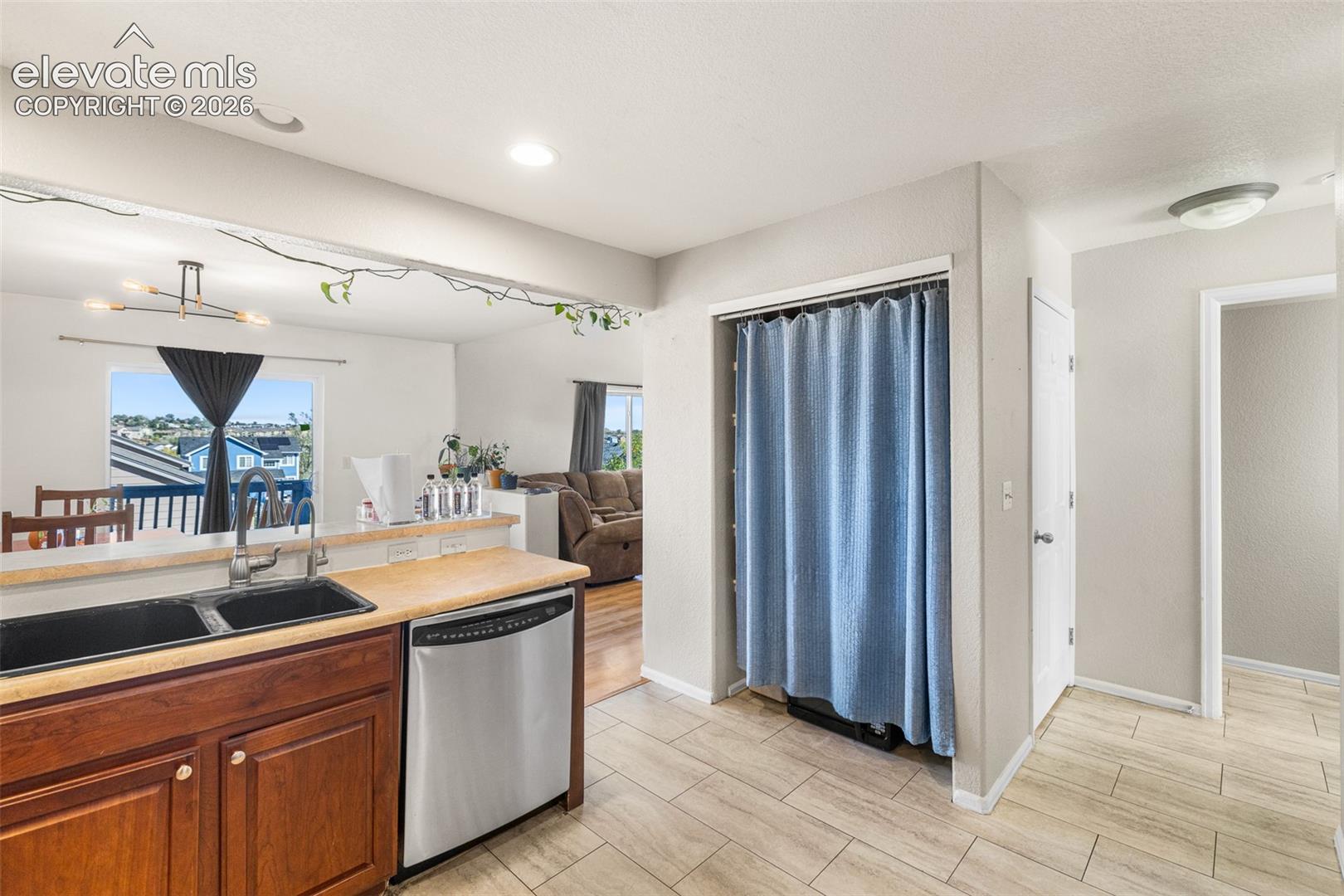 Kitchen featuring wood cabinetry, a dual-basin sink, stainless steel dishwasher, and tile flooring