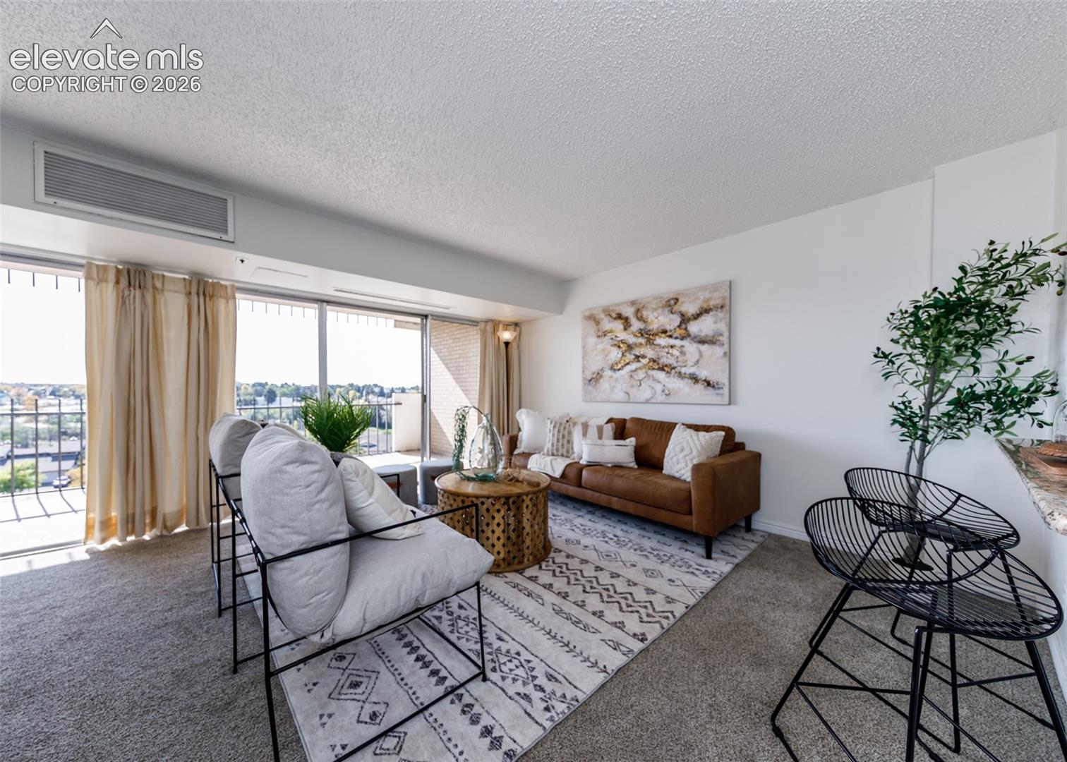 Living space featuring floor-to-ceiling glass sliding doors, private balcony access, neutral wall-to-wall carpeting, and a built-in wall-mounted climate control unit