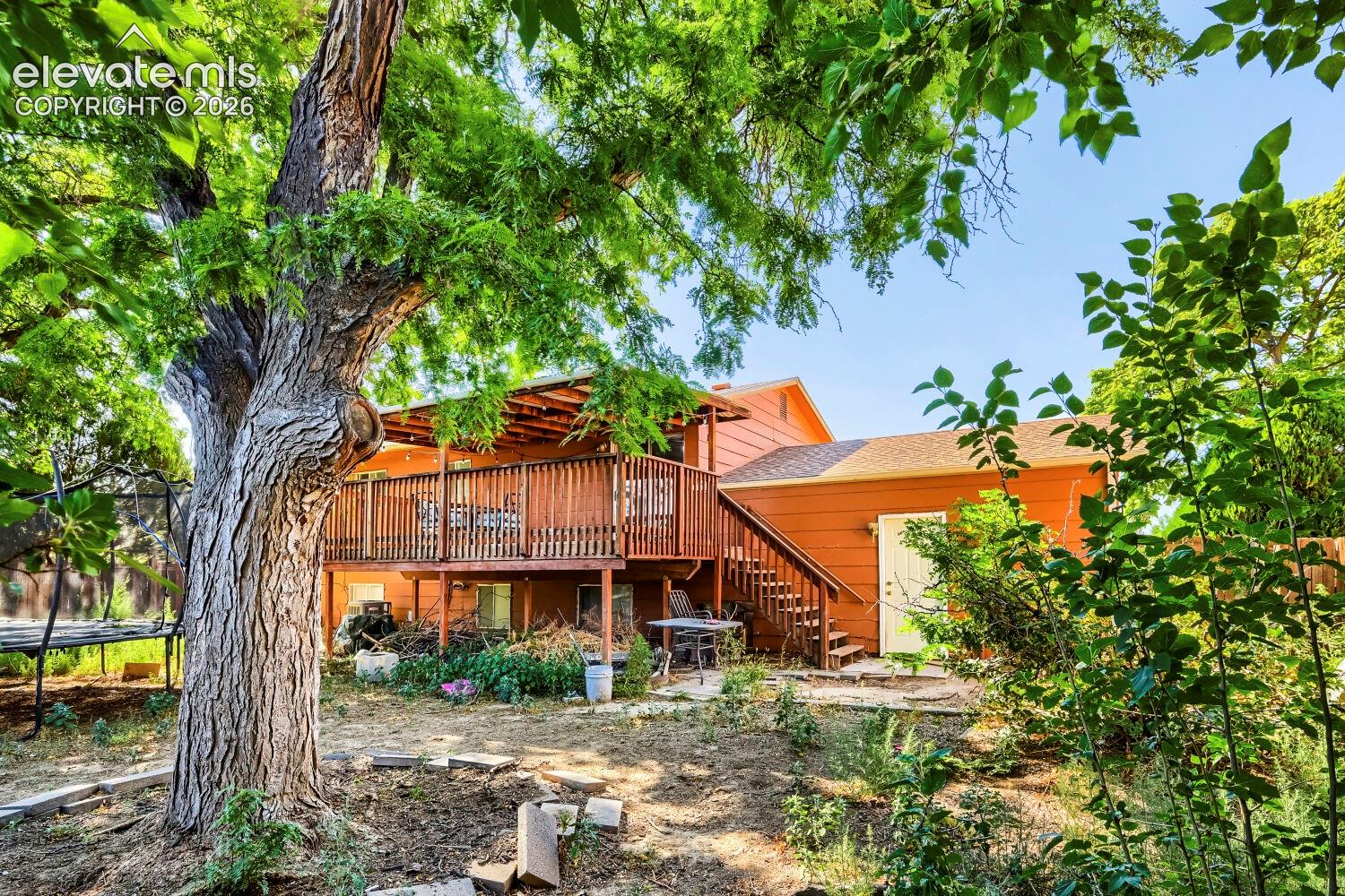 Wood-sided exterior featuring an expansive upper-level deck with wood railing, a covered patio area, and a lower-level concrete patio