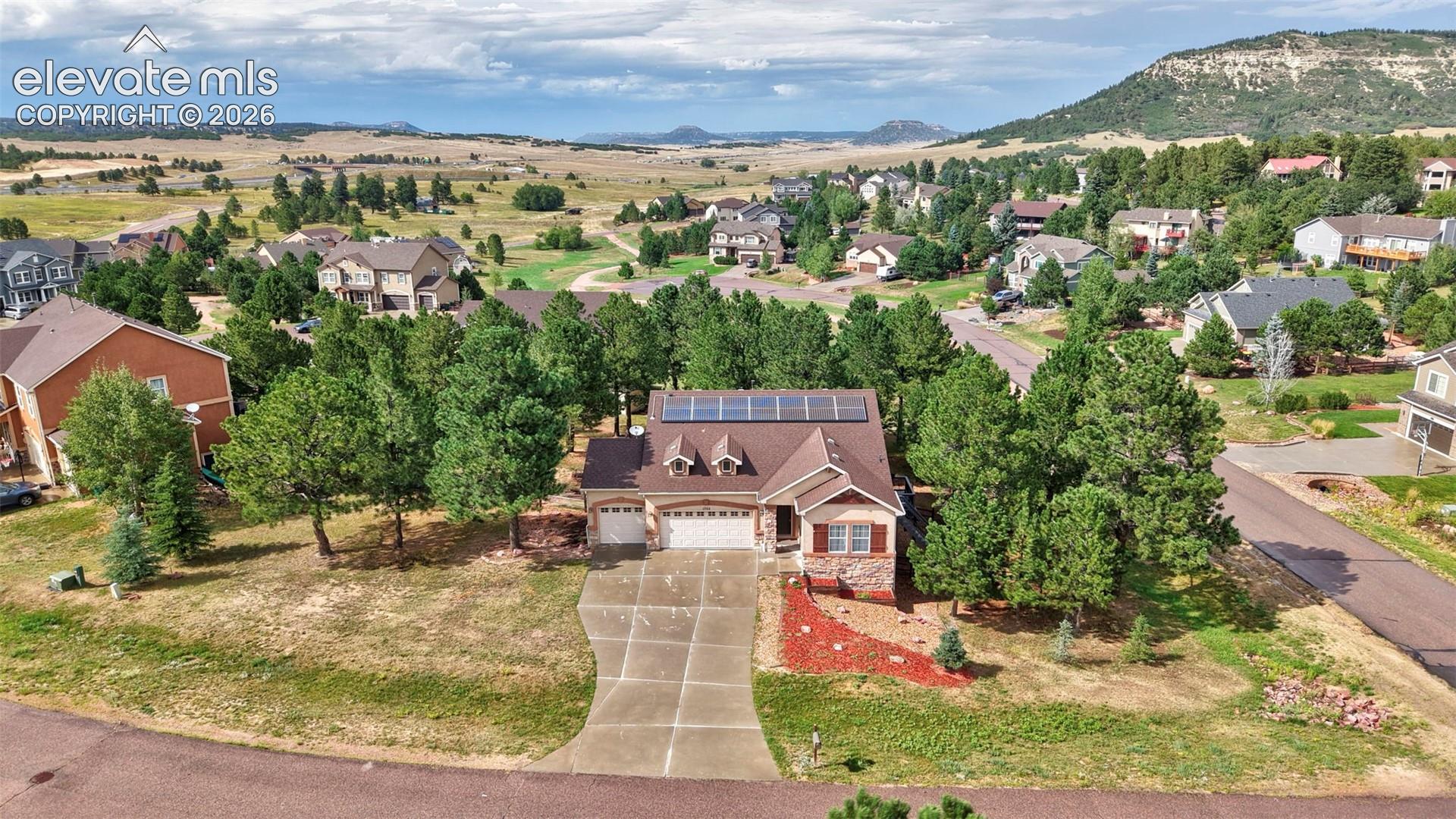 Single-story residence featuring a brown shingle roof with solar panels, stone veneer accents, and a two-car garage