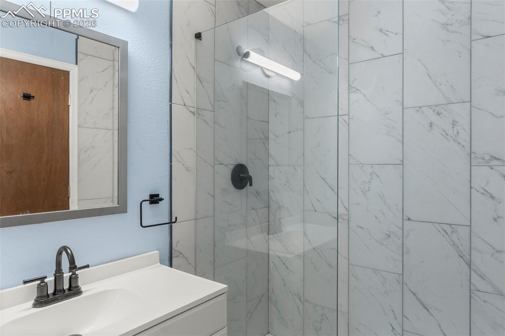 3/4 bathroom featuring vanity and a marble finish WALKIN shower