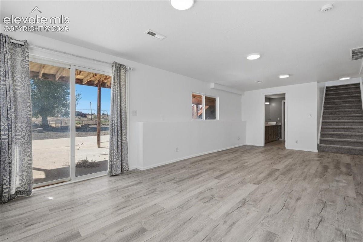 Open-concept room featuring wood-finish flooring, recessed lighting, sliding glass doors, and carpeted stairs