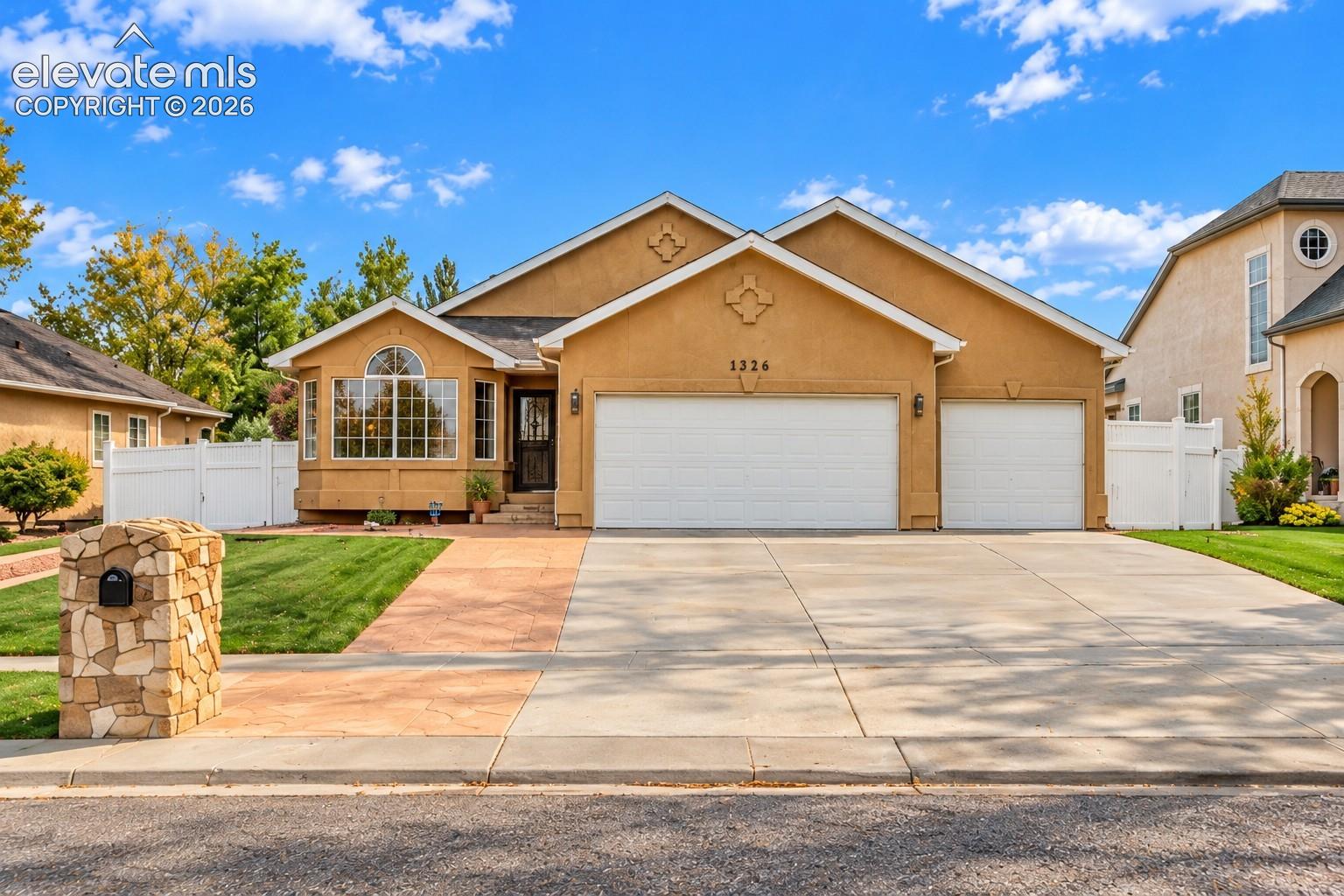 Stucco exterior with decorative gables, expansive three-car garage, stone-veneer mailbox, arched bay window, and concrete driveway
