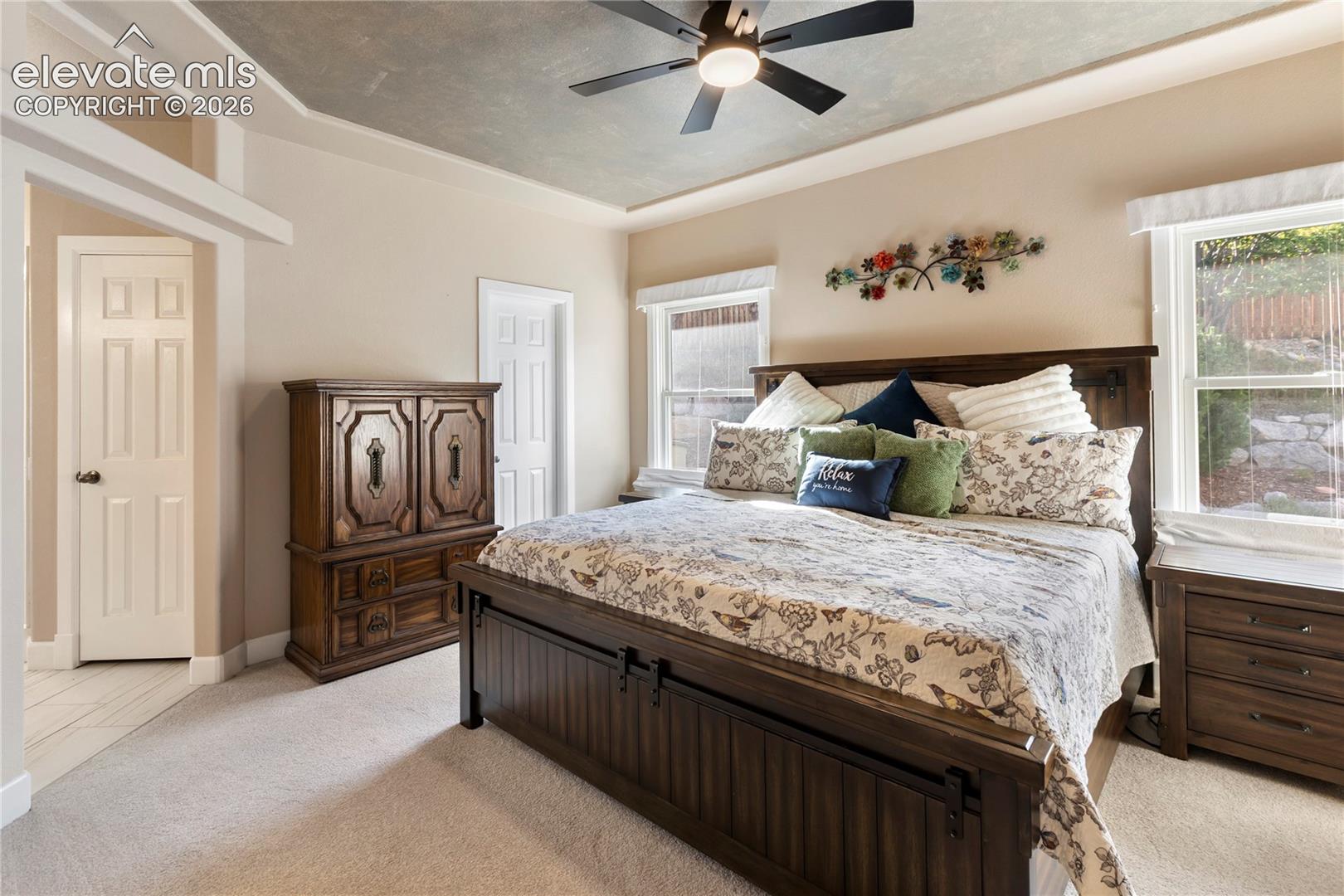 Recessed ceiling with an overhead fan light fixture, two paneled doors, and two windows