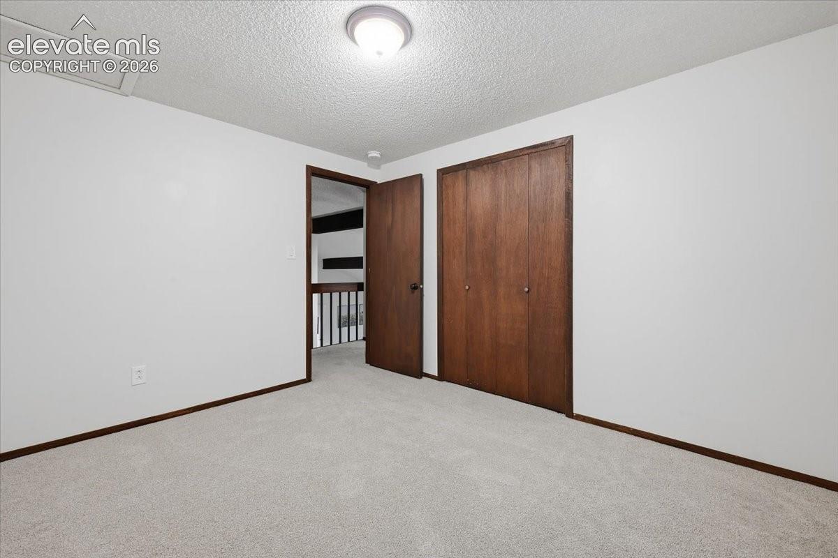 Bedroom 3 - Plush gray carpeting, white walls, and a ceiling-mounted light fixture