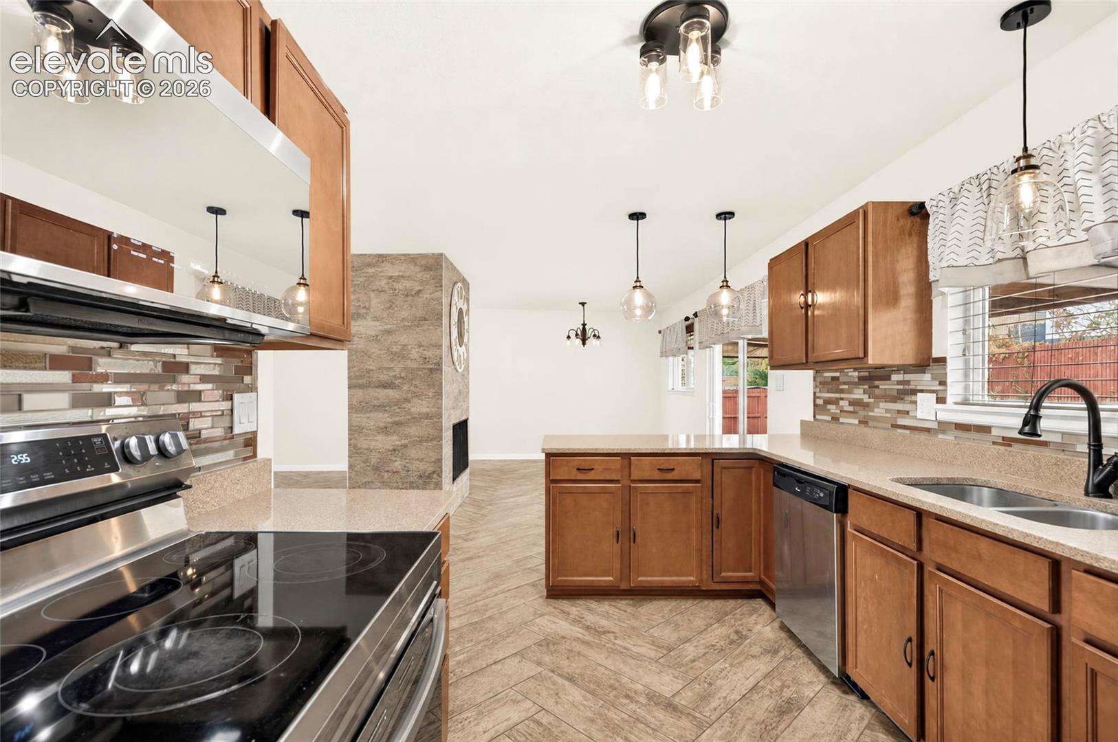 Kitchen featuring wood cabinetry, solid-surface countertops, stone-tile backsplash, stainless steel appliances, and herringbone-patterned flooring
