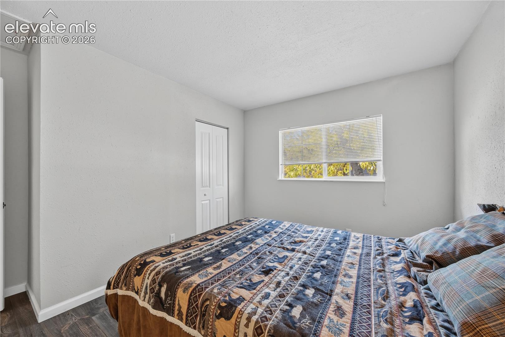 Room featuring wood-finish flooring, a single-panel interior door, and a horizontal sliding window