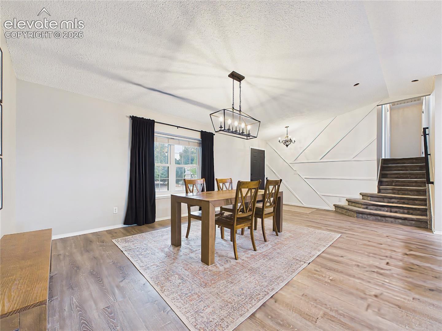 Open dining space overlooking the beautifully updated kitchen with a large center island, abundant cabinetry, and easy access to the enclosed sunroom.