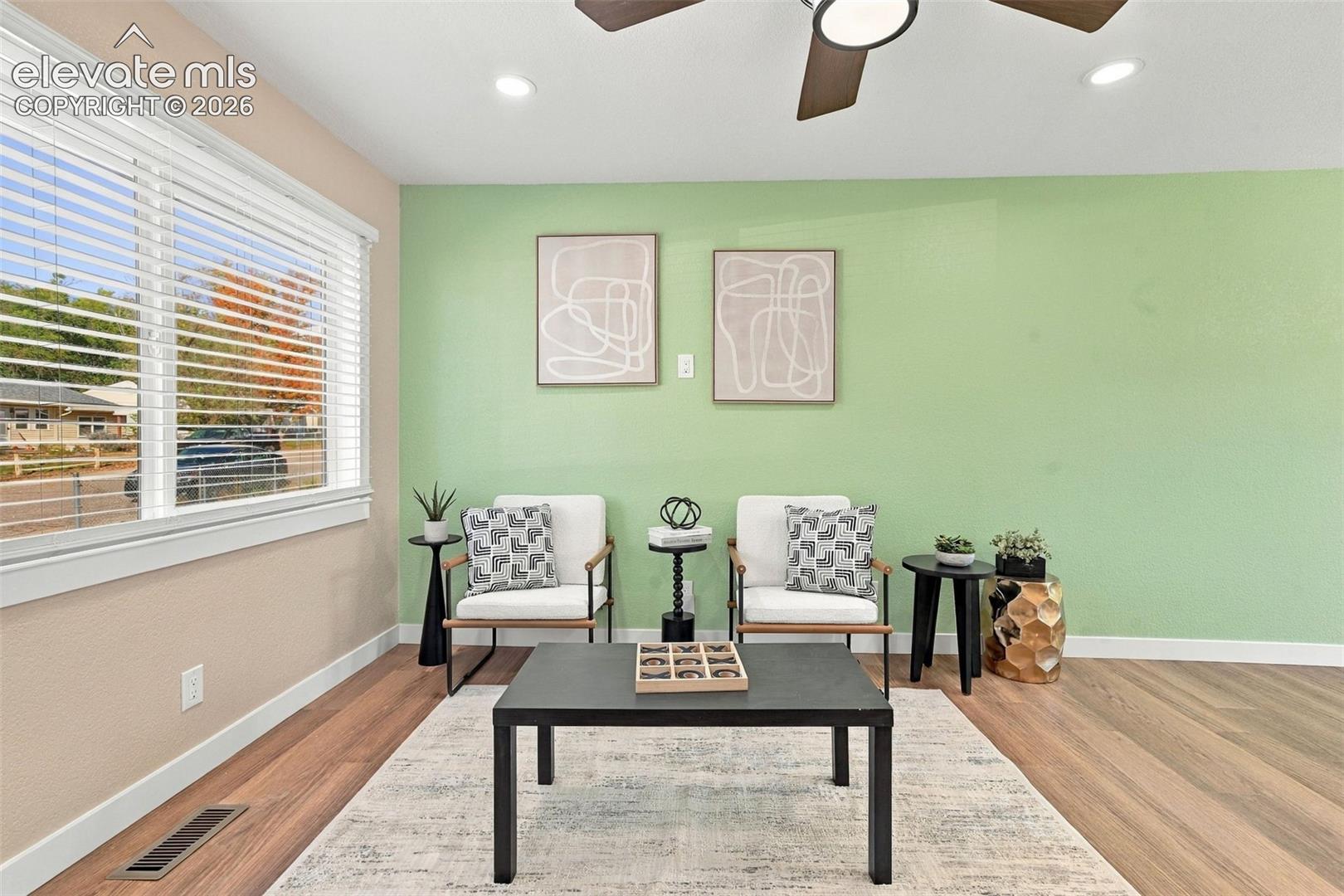 Wood-finish flooring, multi-pane window with horizontal blinds, recessed lighting, and ceiling fan