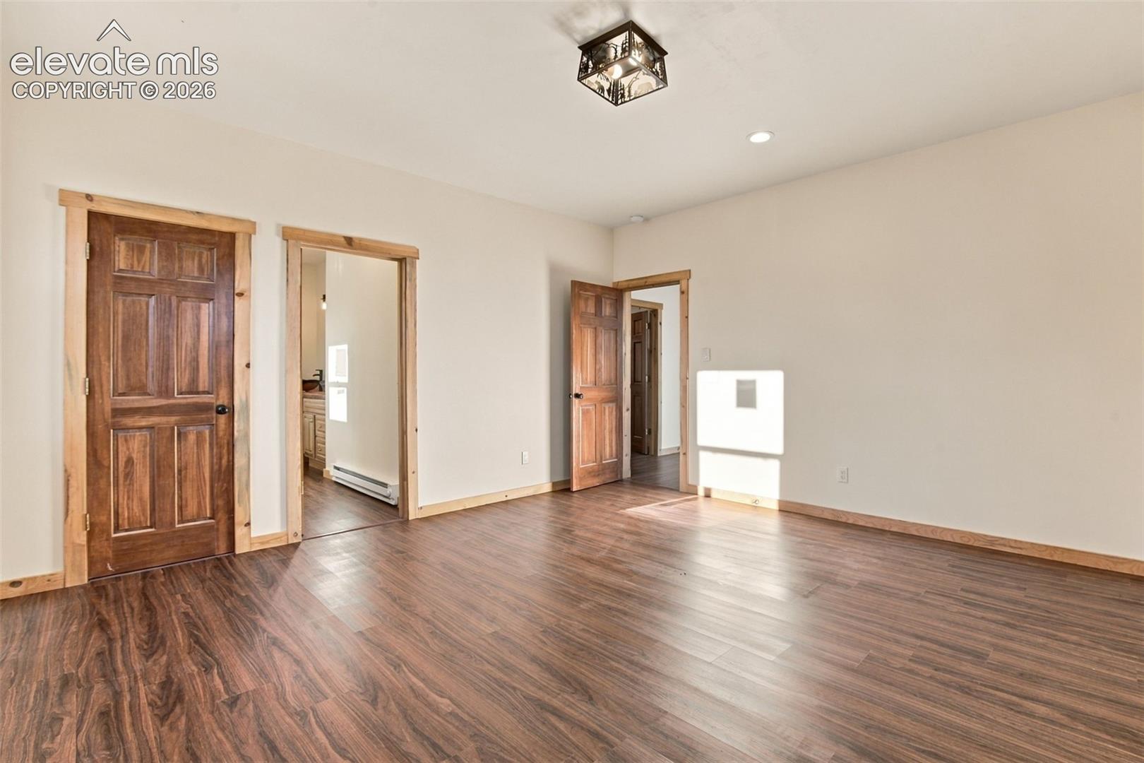 Interior space featuring wood-finish flooring, stained wood interior doors, natural wood door trim, and a decorative geometric ceiling-mounted light fixture