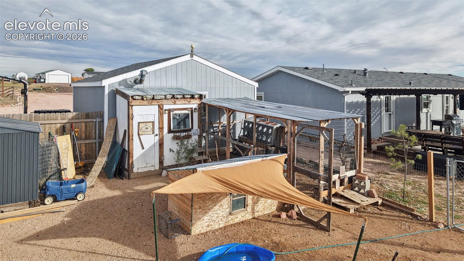 Outdoor space featuring a storage shed with wood trim, a covered wood-frame structure, a corrugated metal roof, and graveled ground surfacing