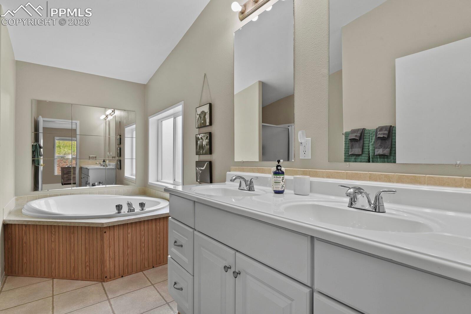 Bathroom with double vanity, a garden tub, light tile patterned floors, and a shower stall