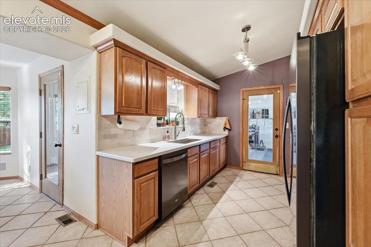 Kitchen featuring wood cabinetry, white countertops, tile backsplash, and tile flooring