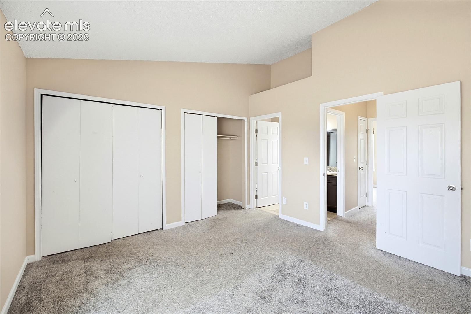 Double closets in the Primary Bedroom and view into the adjoining Full Bathroom.