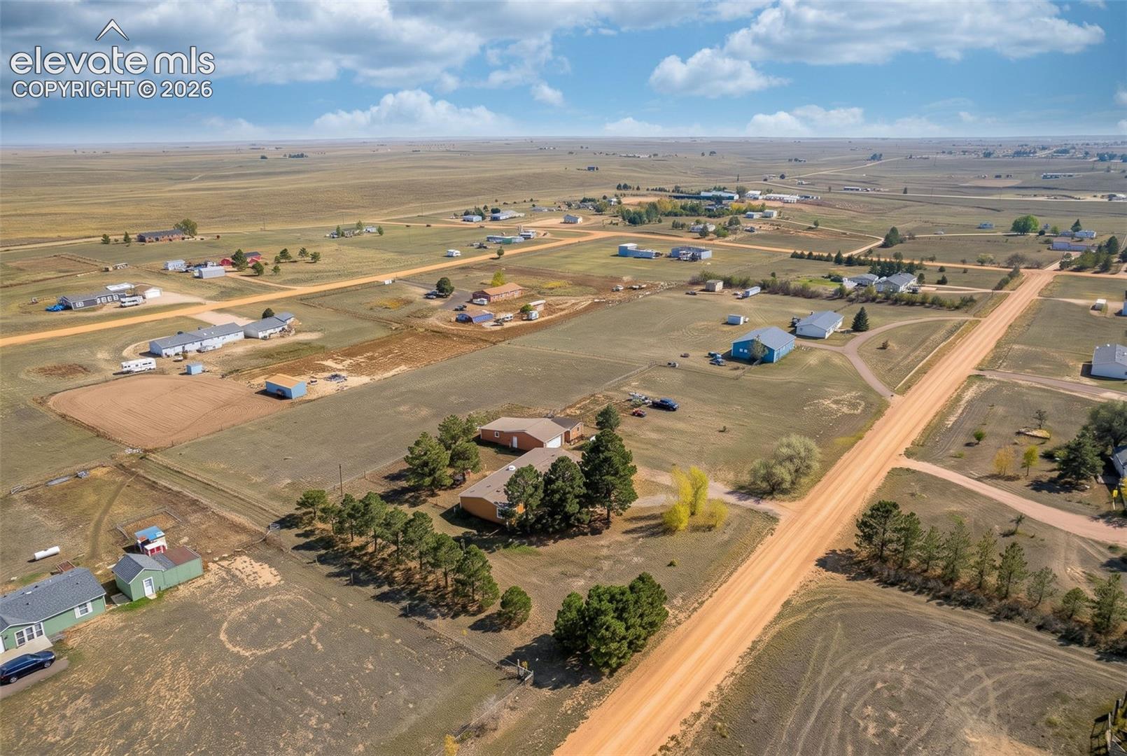 Aerial perspective of rural acreage featuring an expansive open landscape, mature trees, and direct access to a secondary roadway