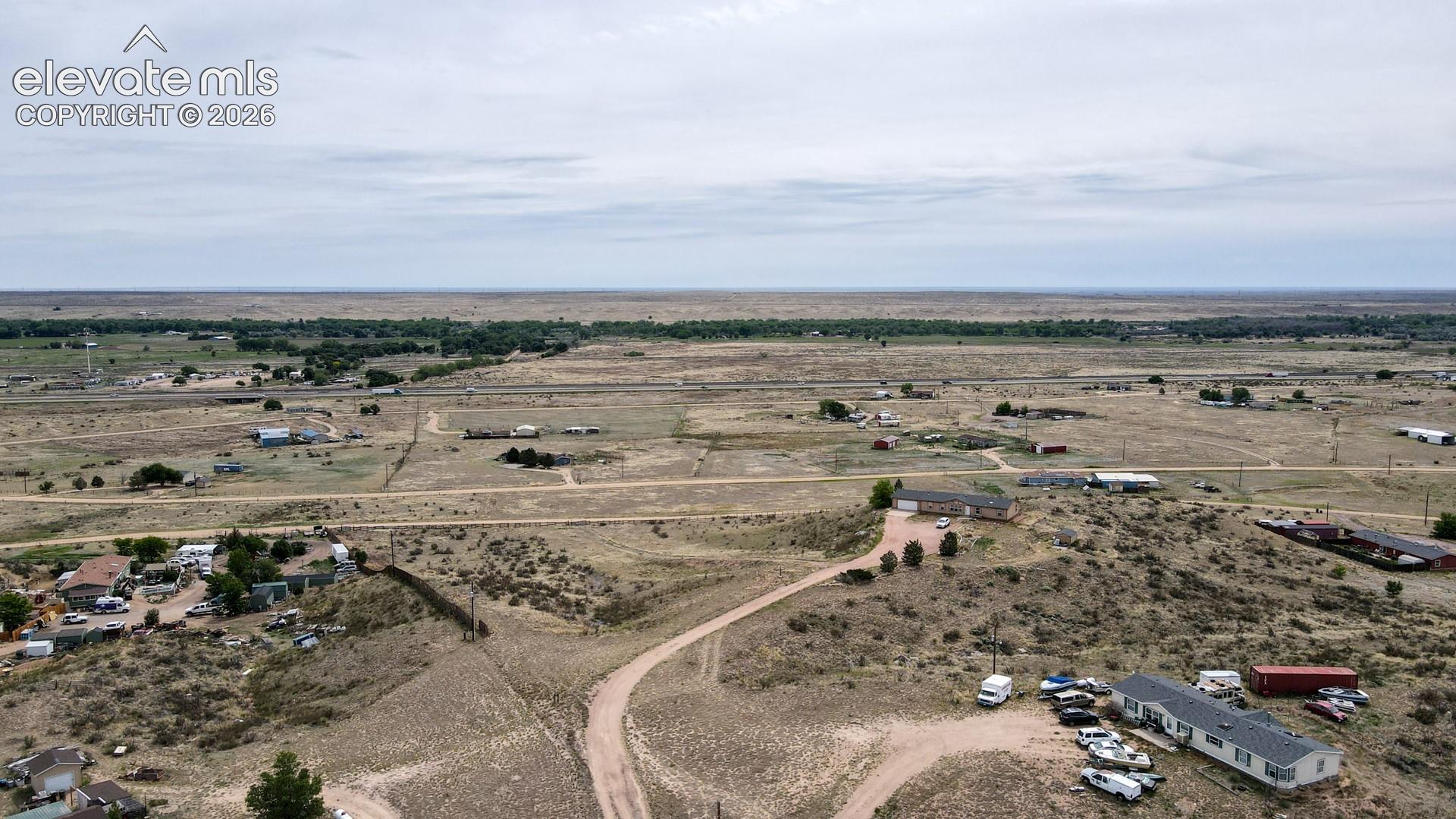 Expansive undeveloped land featuring scattered residential structures and various accessory buildings, with a visible dirt road network