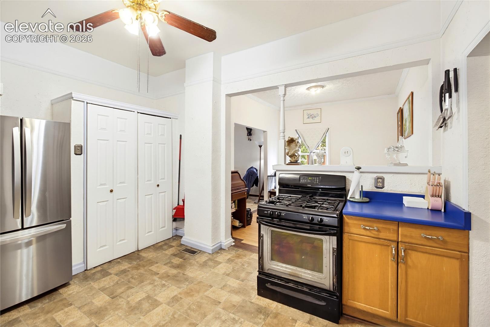 Kitchen featuring a gas range, wood-finish flooring, wood cabinetry, and a ceiling fan with integrated lighting