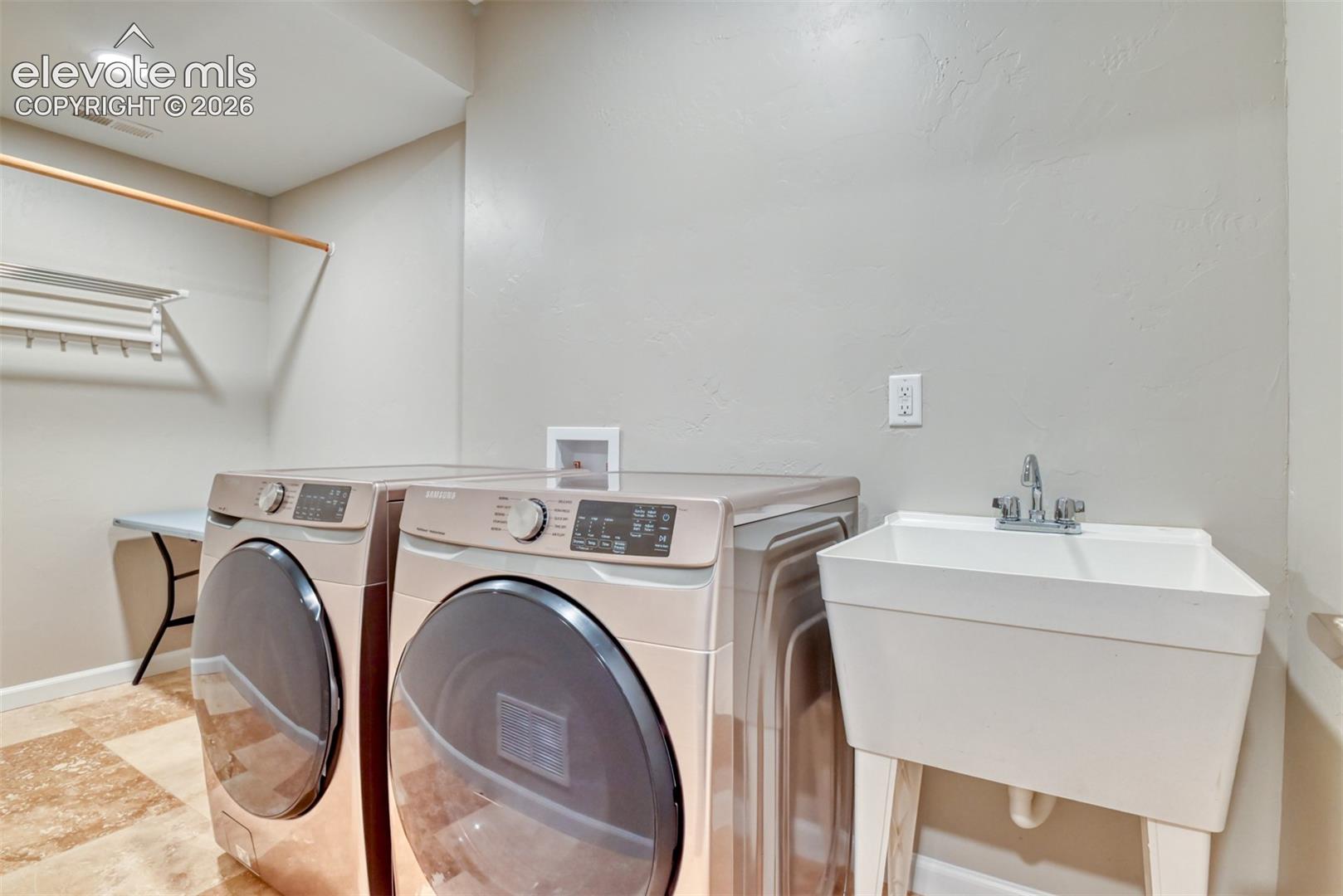 Utility sink with chrome faucet, overhead recessed lighting, and tile flooring. Downstairs laundry room.
