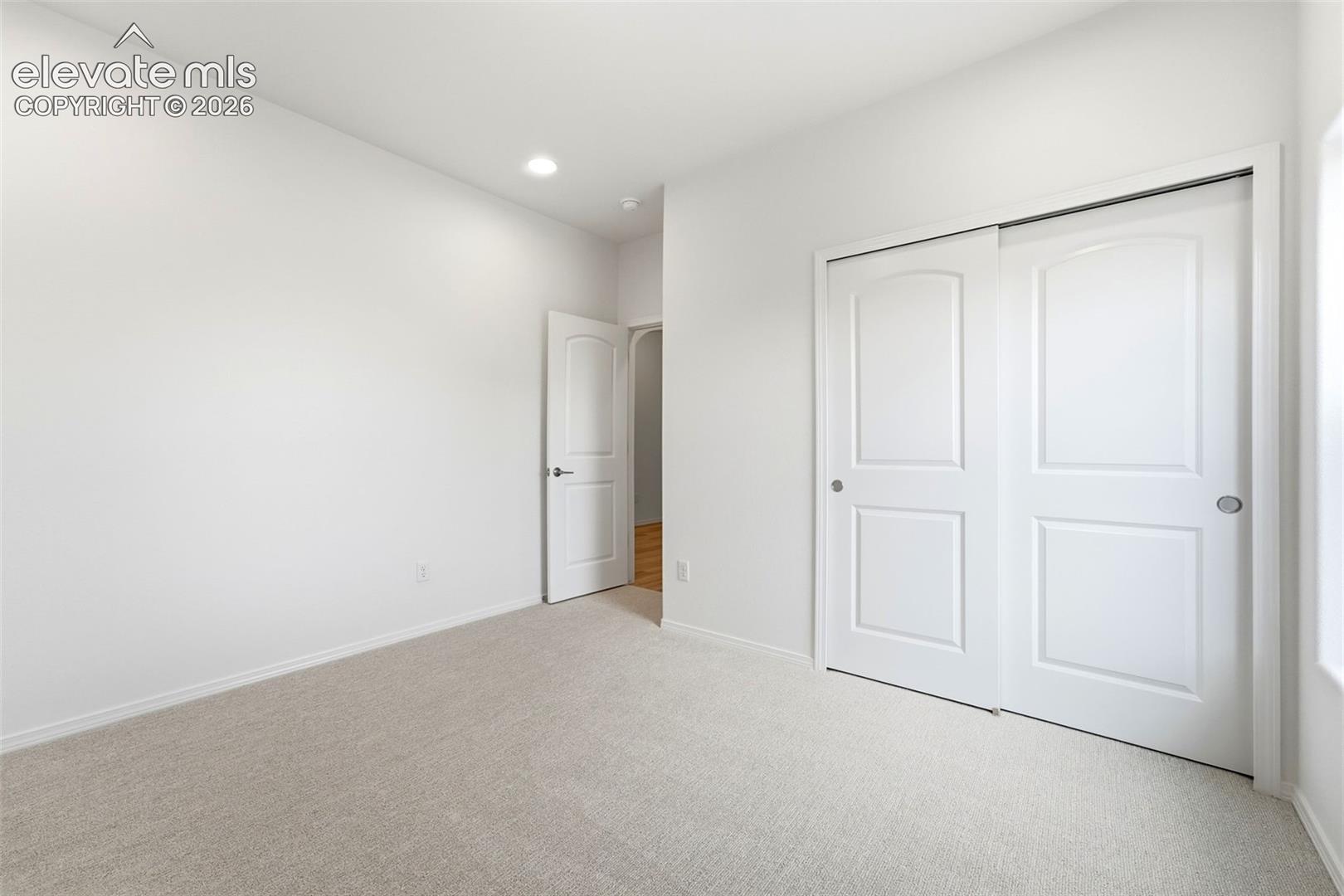 Neutral interior featuring wall-to-wall carpeting, recessed lighting, and a closet with white paneled sliding doors