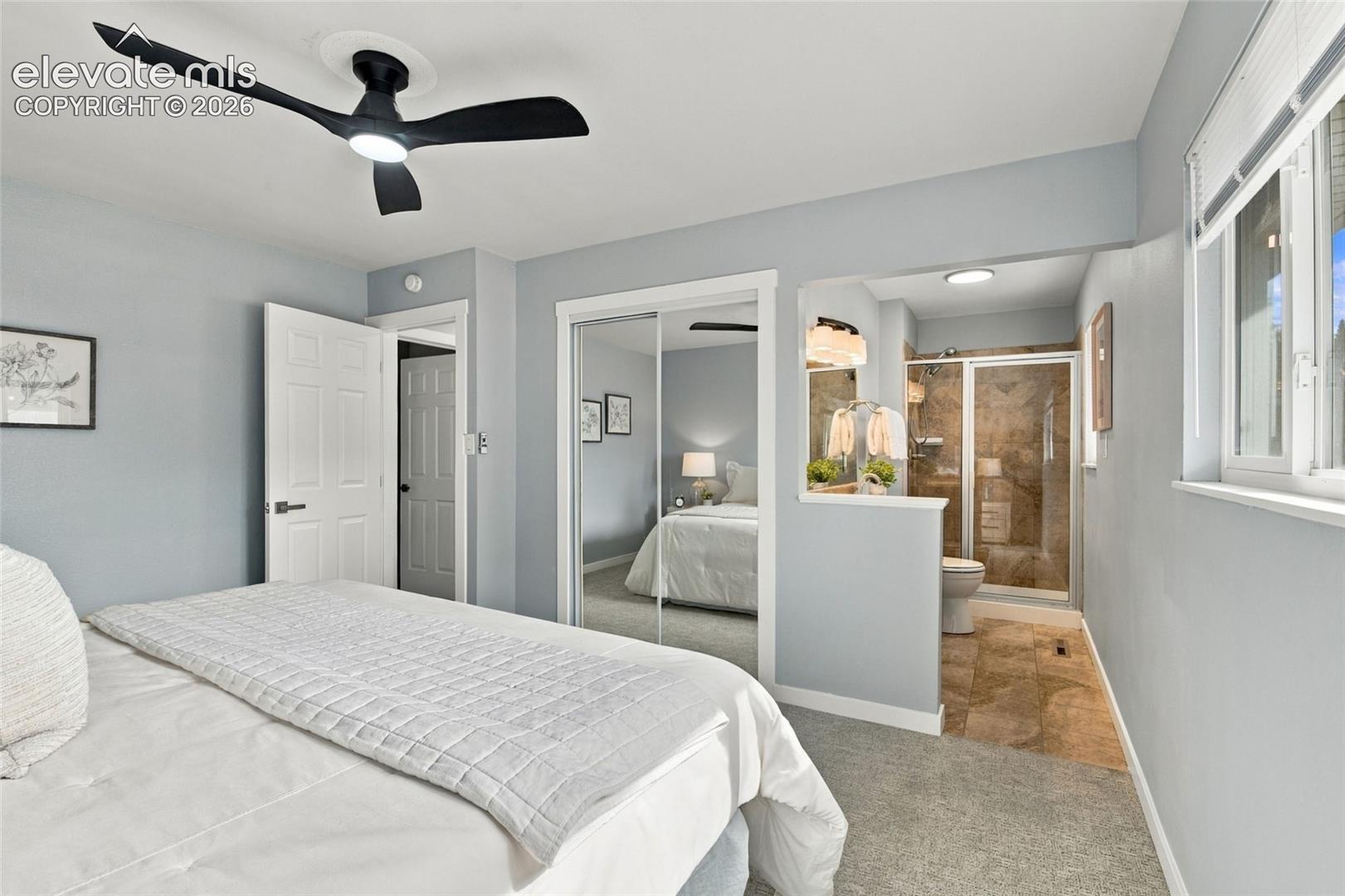 Room featuring a matte black three-blade ceiling fan, sliding mirrored closet doors, and wall-to-wall carpeting