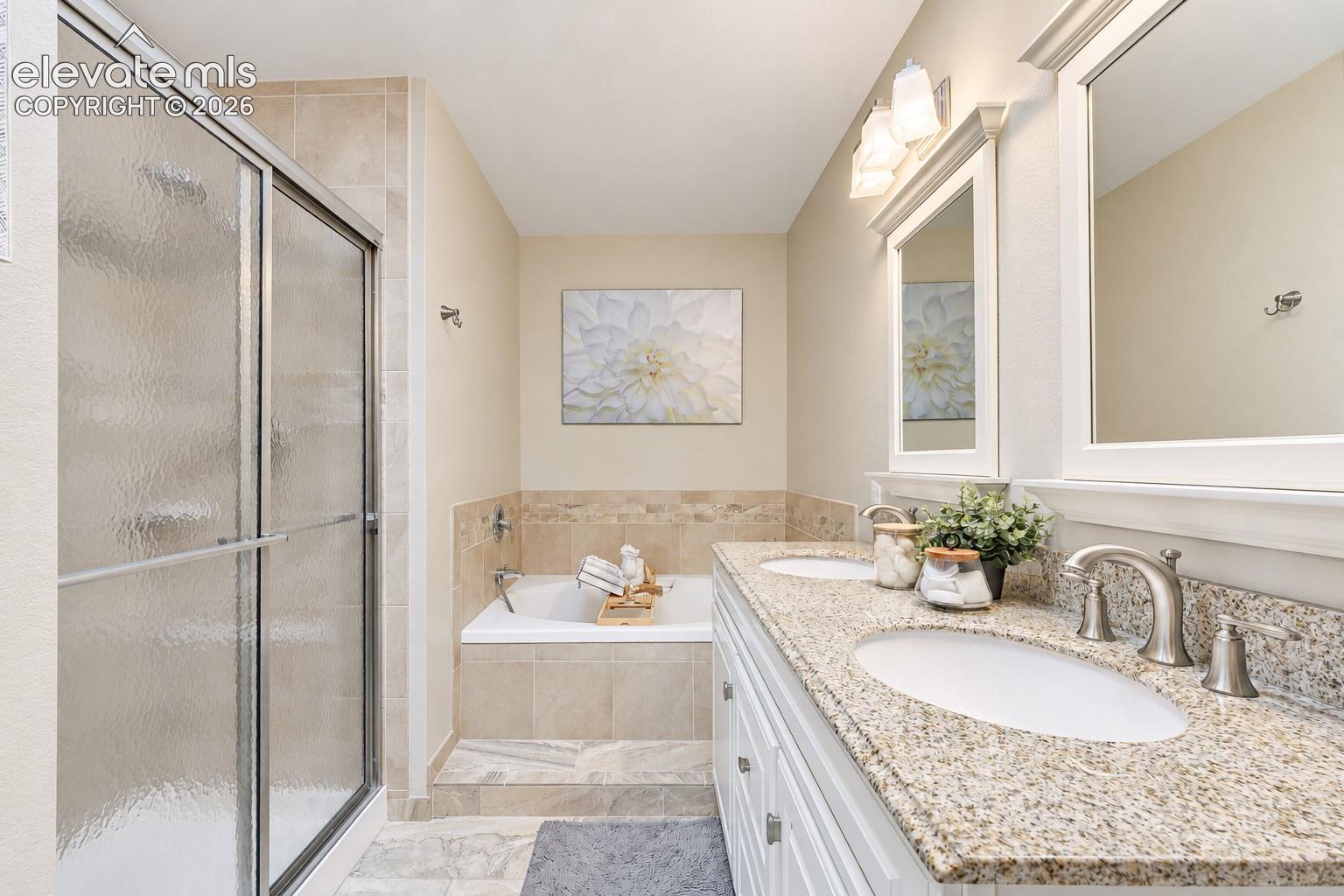 Spa like 5pc Primary Bathroom with dual sink vanity, framed mirror, soaking tub, and separate shower.