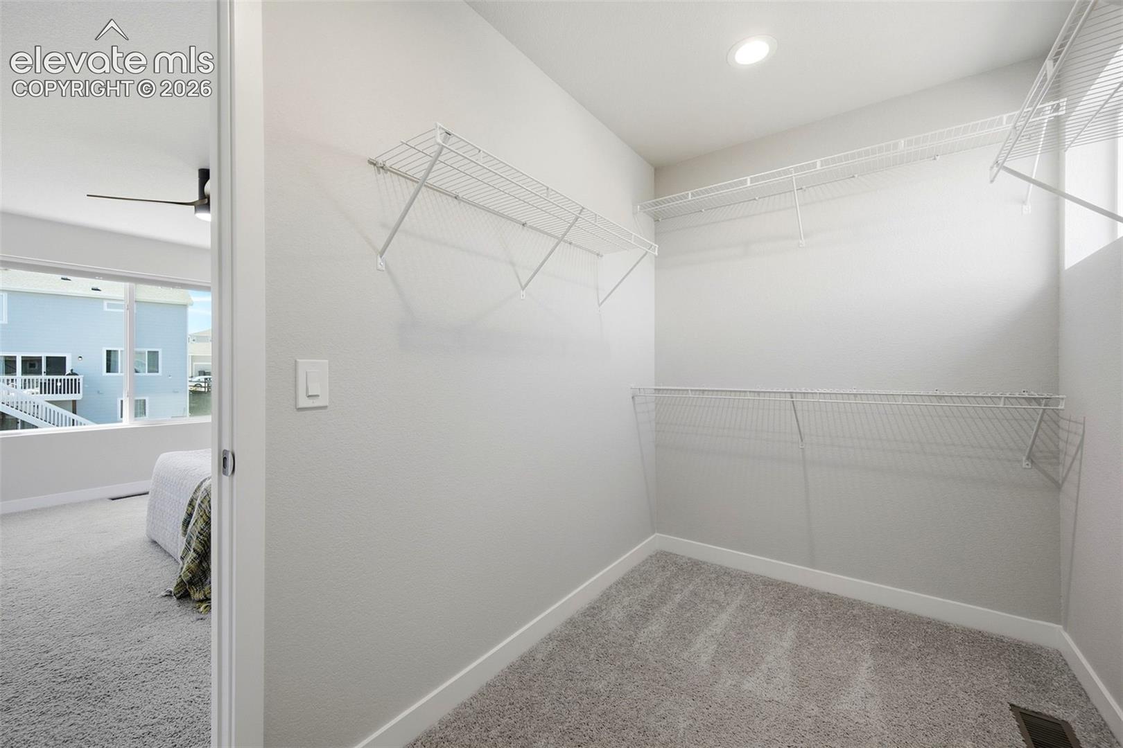 Primary walk in closet with window and built in shelving