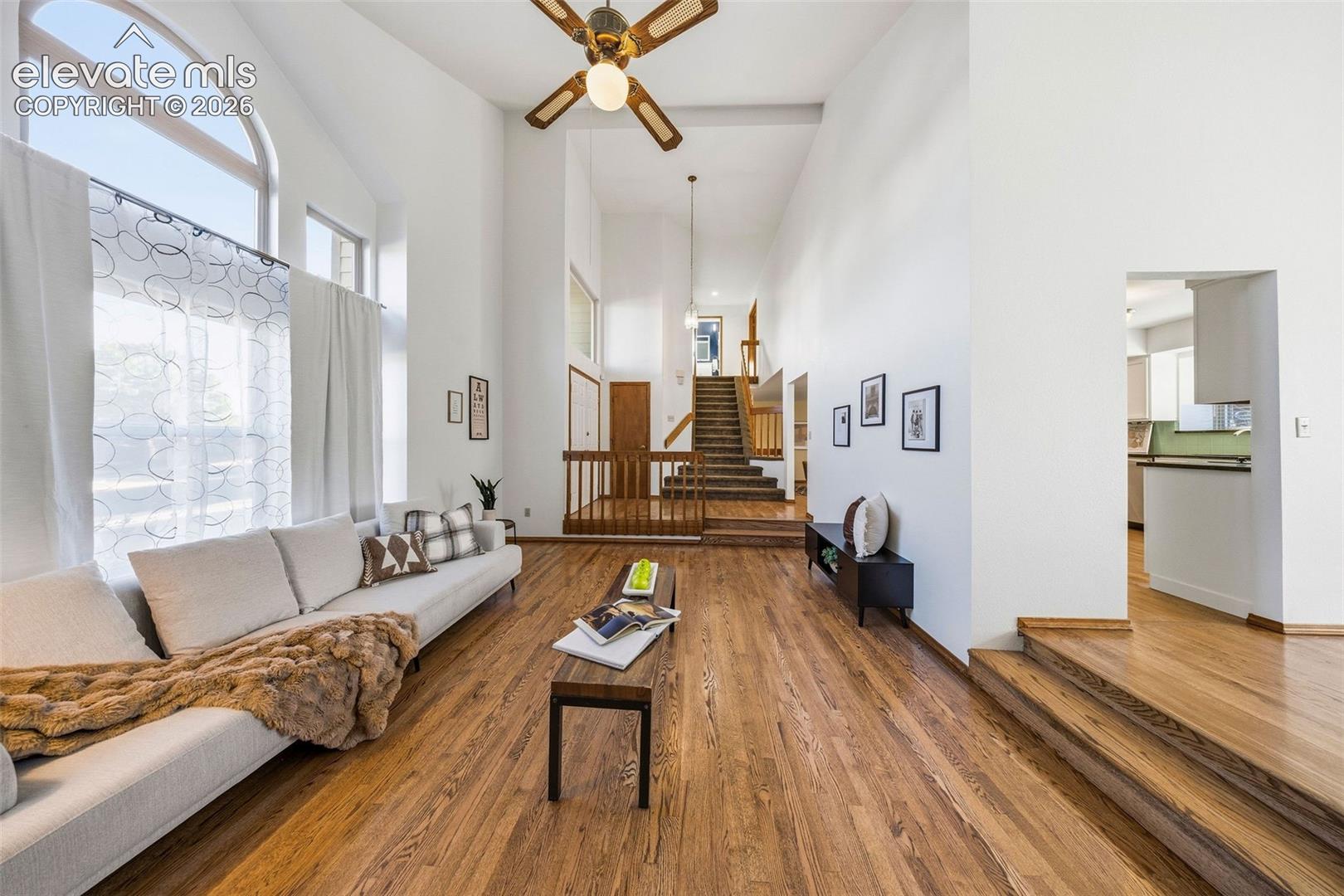 Vaulted ceilings, expansive arched windows, wood-finish flooring, and multi-level design featuring wooden railings and stairs