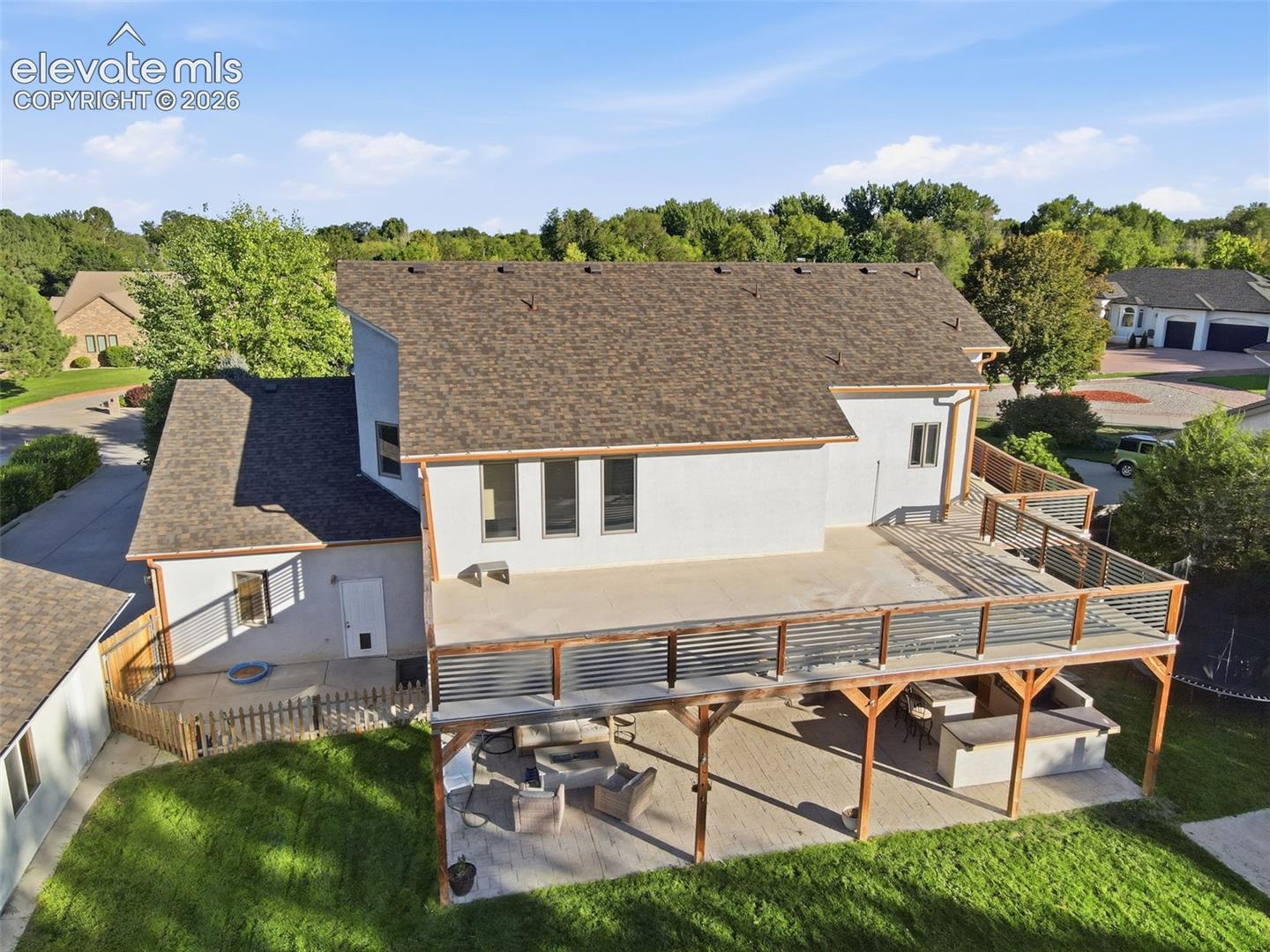 Expansive outdoor living space featuring a multi-level deck with wood and metal railings, a covered patio area, and an integrated outdoor kitchen structure