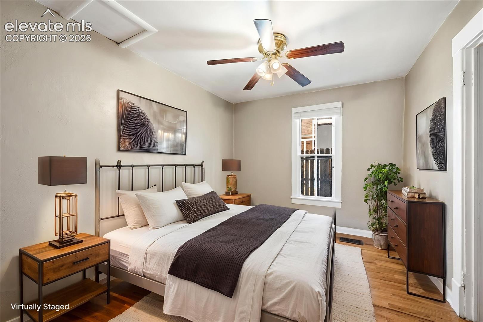 Room featuring wood-finish flooring, a multi-blade ceiling fan with integrated lighting, and a single-hung window with white casing
