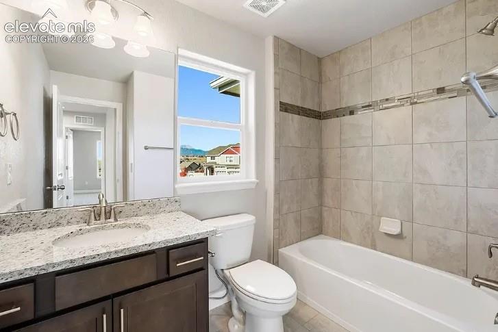 Bathroom featuring a dark wood-finish vanity with a stone countertop, an oversized wall mirror, three-bulb vanity light fixture, and a tile-surround shower and tub combination with a decorative inlay