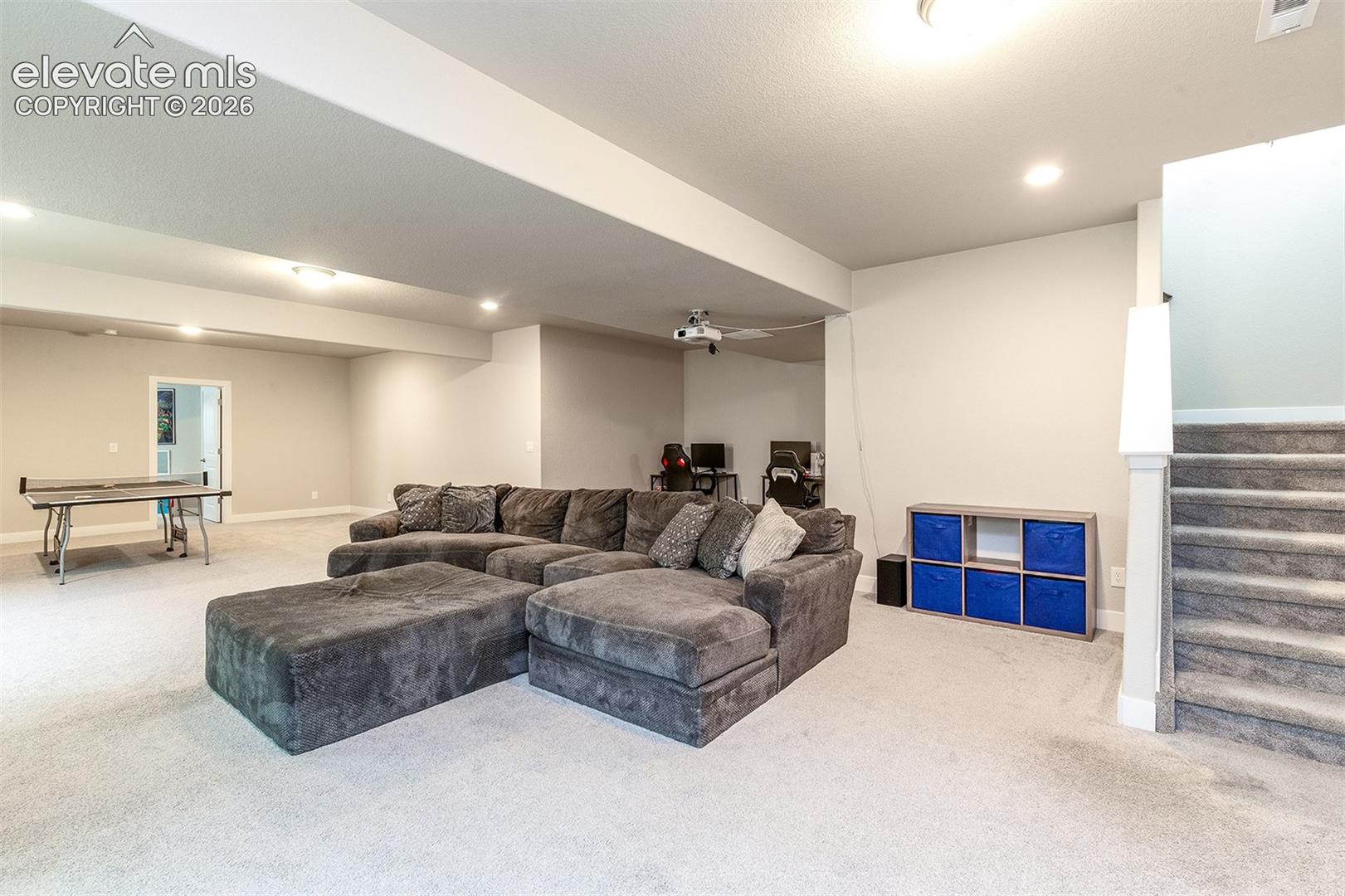 Spacious carpeted room featuring recessed lighting and a built-in staircase