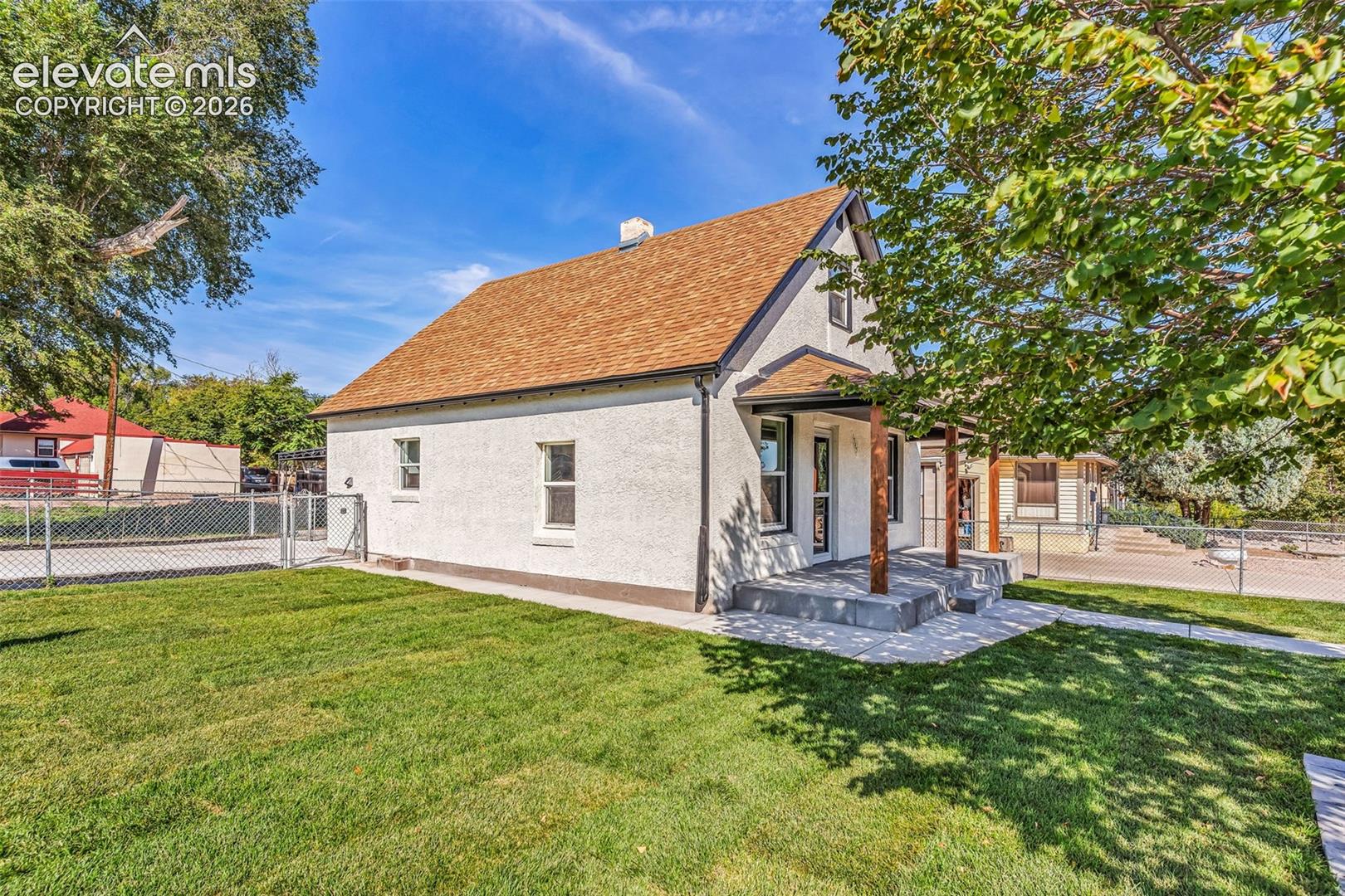 Stucco exterior featuring a gabled roof, covered front porch with timber posts, and concrete walkway