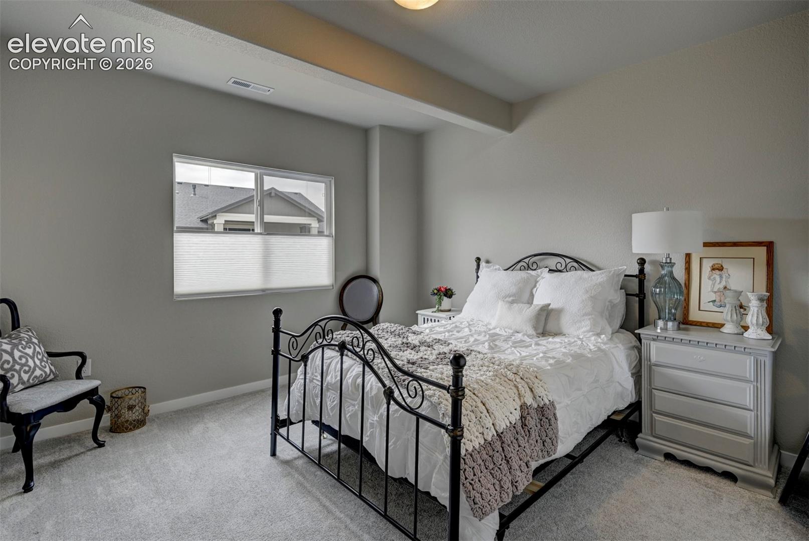Plush carpet flooring, neutral painted walls, and a multi-pane window with privacy blinds