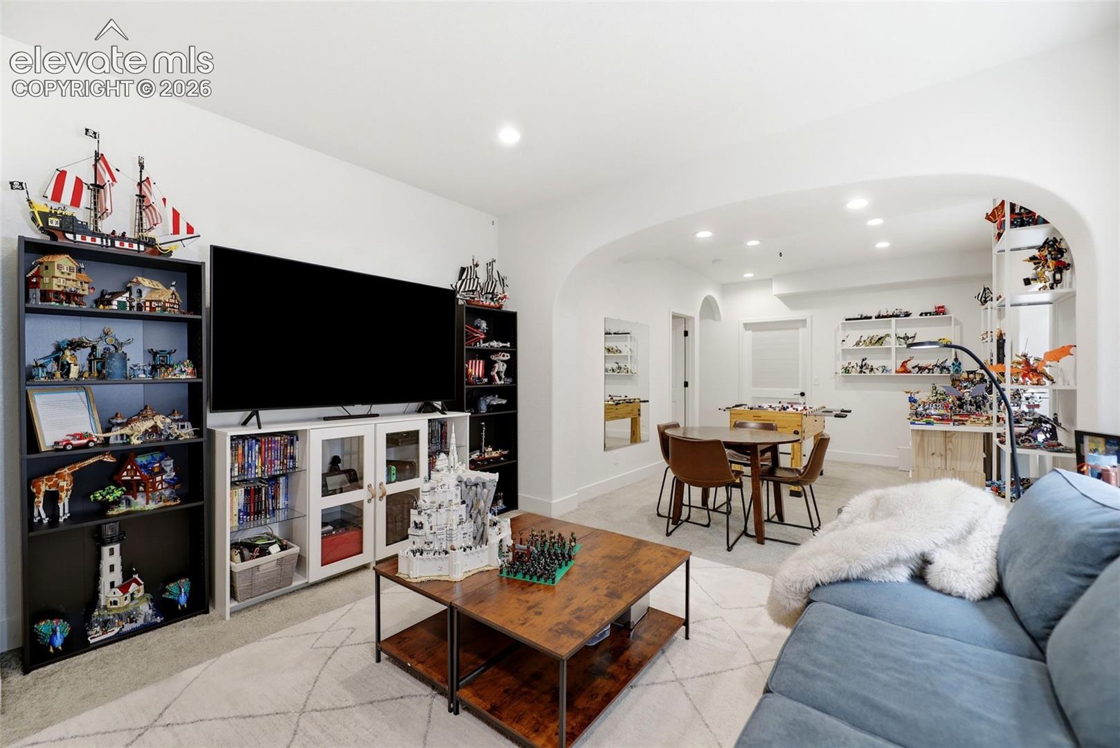 Recessed lighting illuminates an open-concept entertainment space featuring an arched entryway.