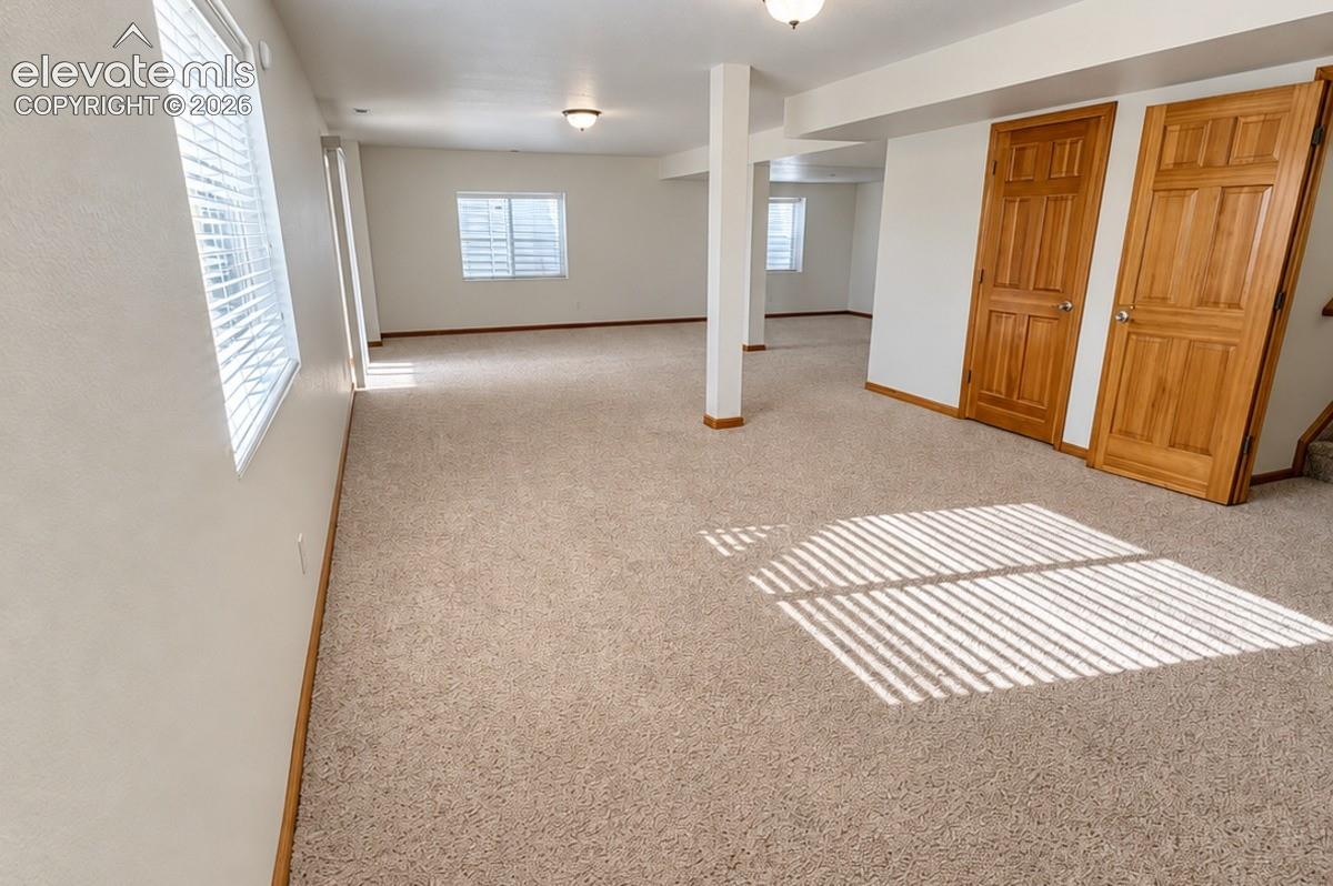 Expansive carpeted area with multiple windows, recessed lighting, and solid wood panel doors