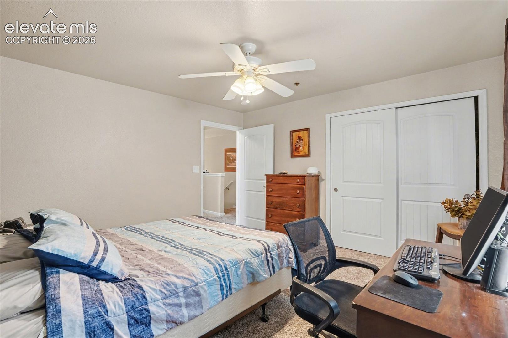 Bedroom featuring carpeting, a ceiling-mounted light fixture with a fan, and dual-panel interior doors