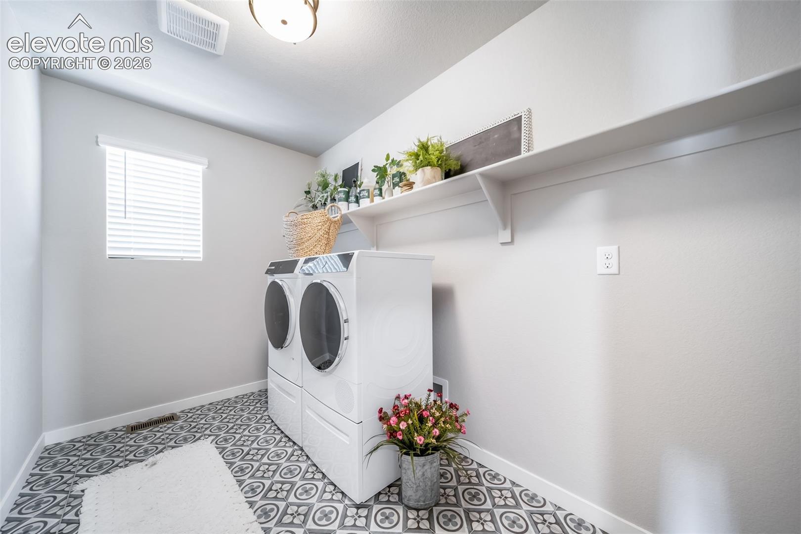 Laundry room featuring patterned floor tiles, a window with blinds, overhead light fixture, and a built-in wall shelf
*Photos of a model home*