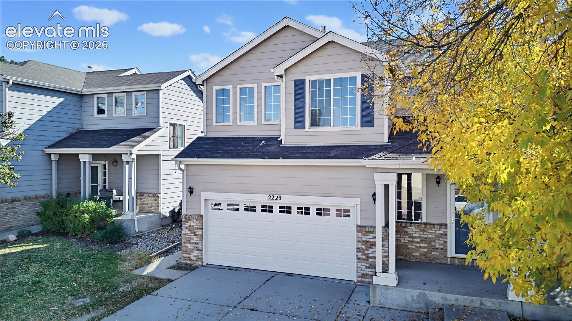 Two-story residence featuring horizontal siding, a stone veneer facade, a multi-paneled garage door, and a covered front entry porch with structural columns