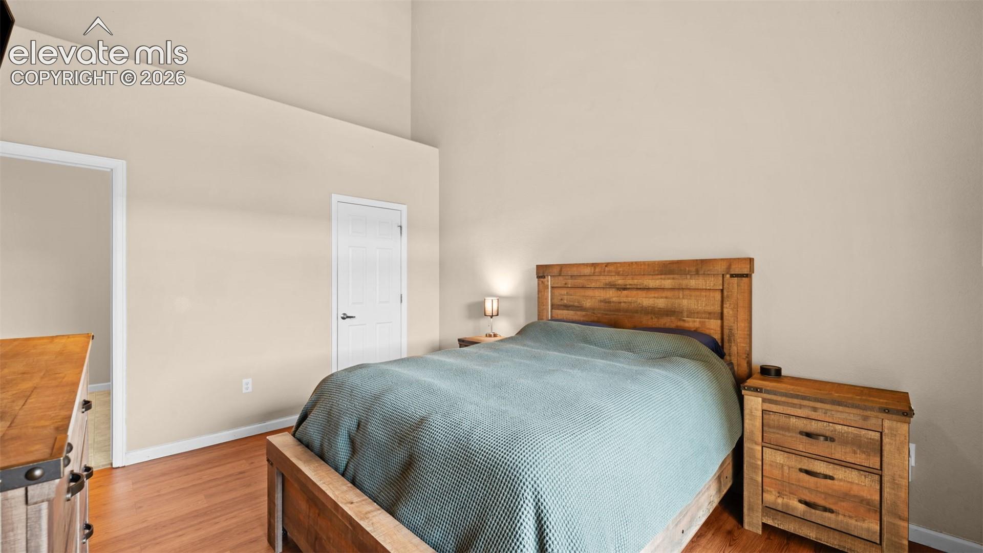 Bedroom featuring vaulted ceilings, wood-finish flooring, and a neutral color palette