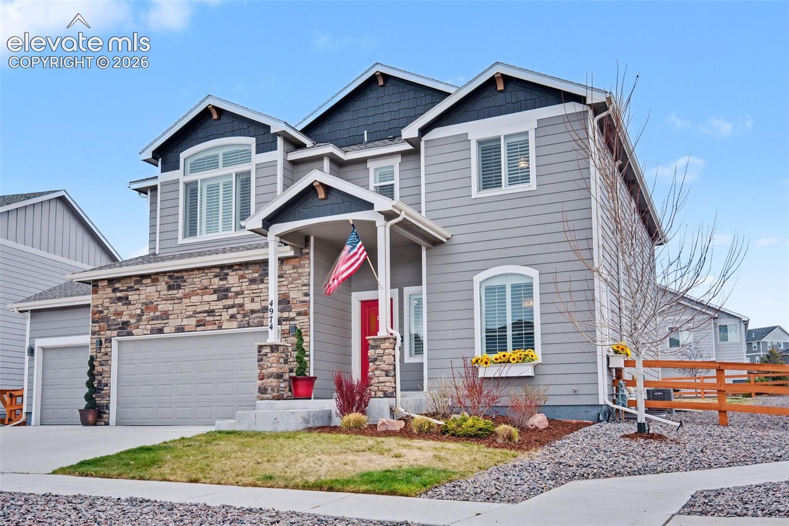 Grey siding exterior with stone accents, covered front porch, and an attached two-car garage