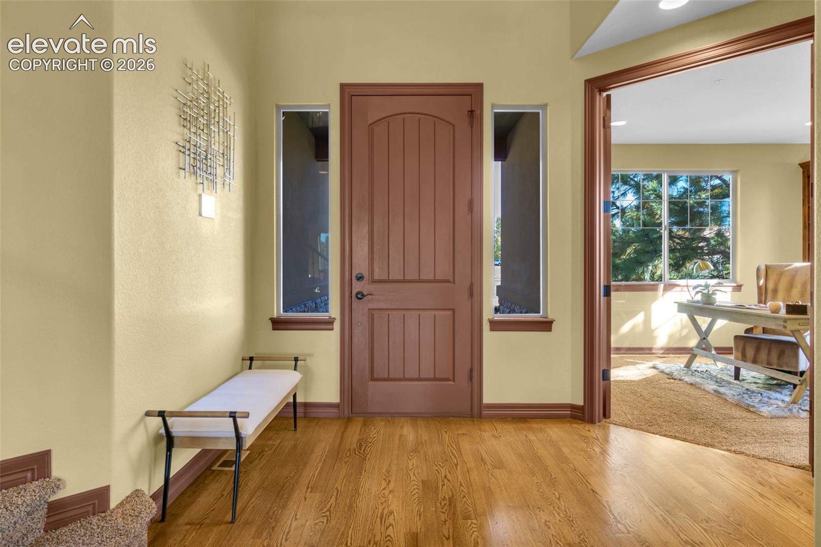 Entryway featuring a solid wood-finish arched-top front door, dual side windows, wood-finish flooring, and crown molding