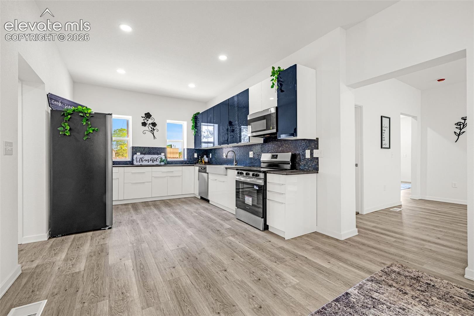 Modern kitchen featuring white cabinetry, dark countertops, and a full suite of stainless steel appliances