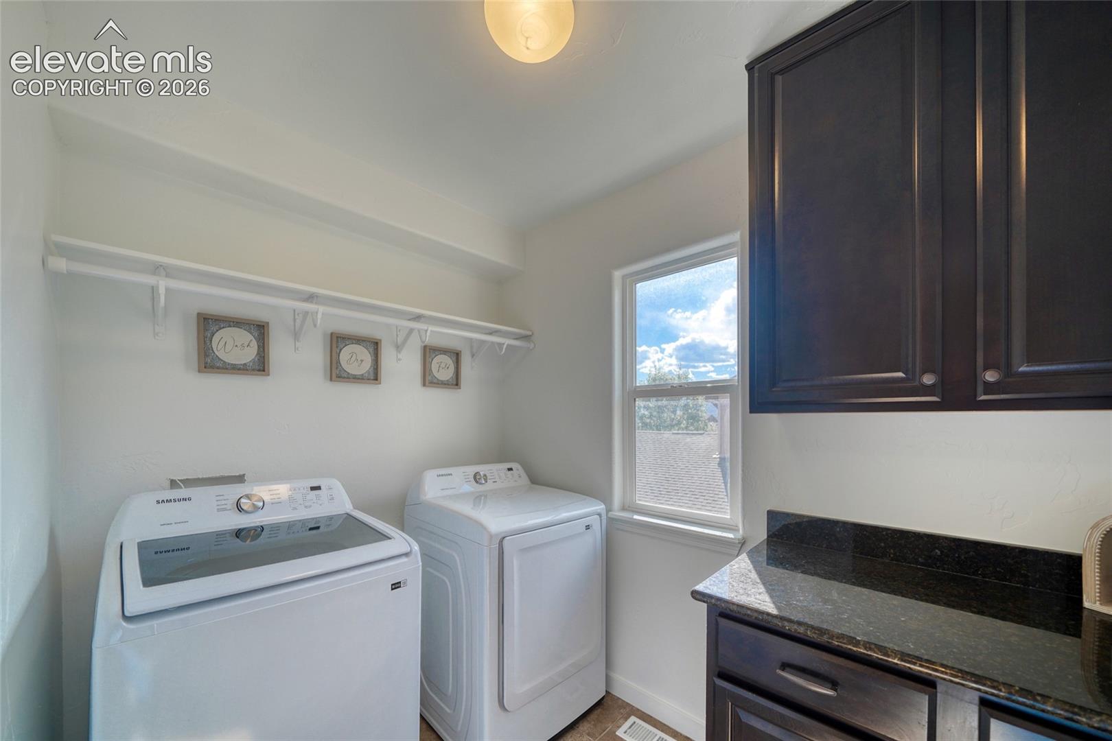 Laundry room with built-in shelving, dark wood-finish cabinetry, and a window