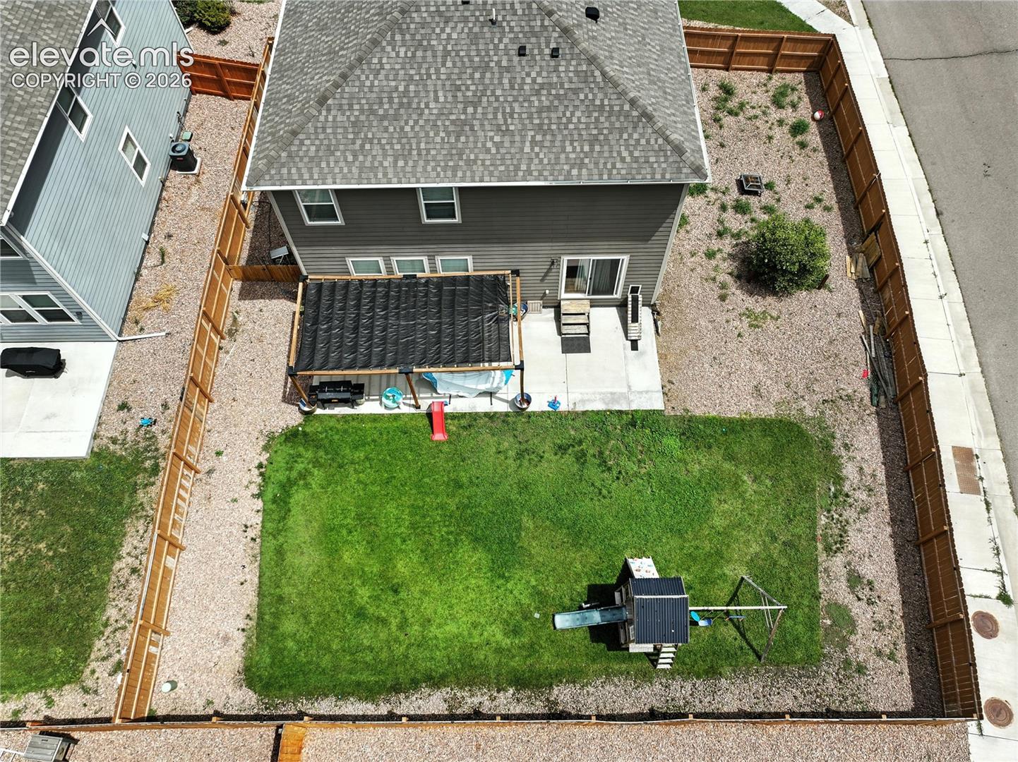 Expansive backyard with a manicured lawn, gravel landscaping, and wood privacy fencing