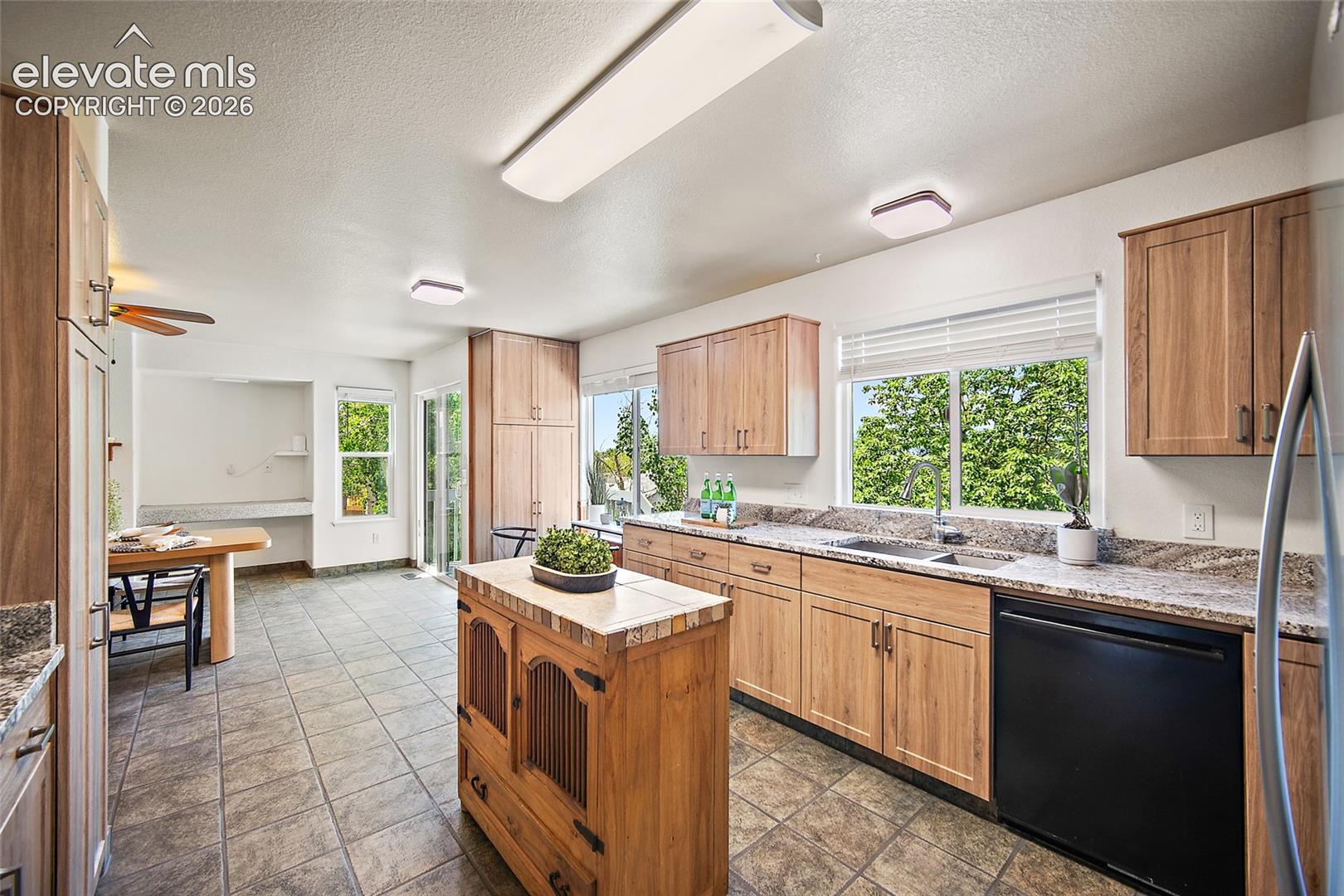 Kitchen featuring wood-finish cabinetry, stone-look countertops, and tile flooring