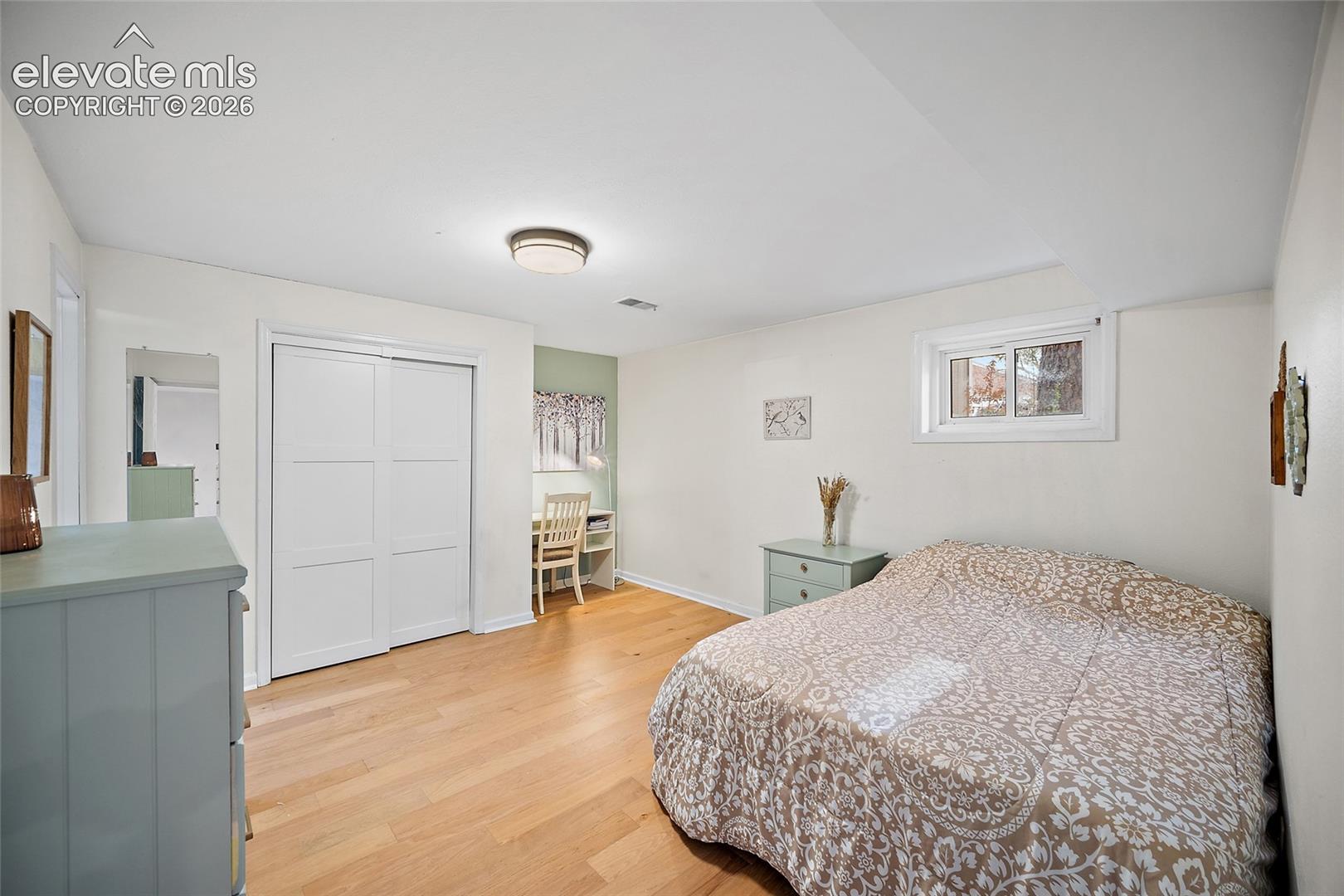 Room featuring wood-finish flooring, sliding-door closet, neutral wall tones, and recessed ceiling lighting