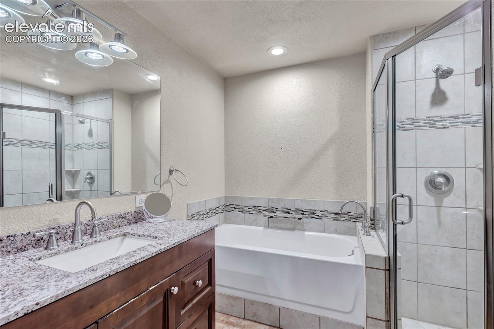 Bathroom featuring a dark wood-finish vanity with a single basin, granite countertop, and polished chrome fixtures