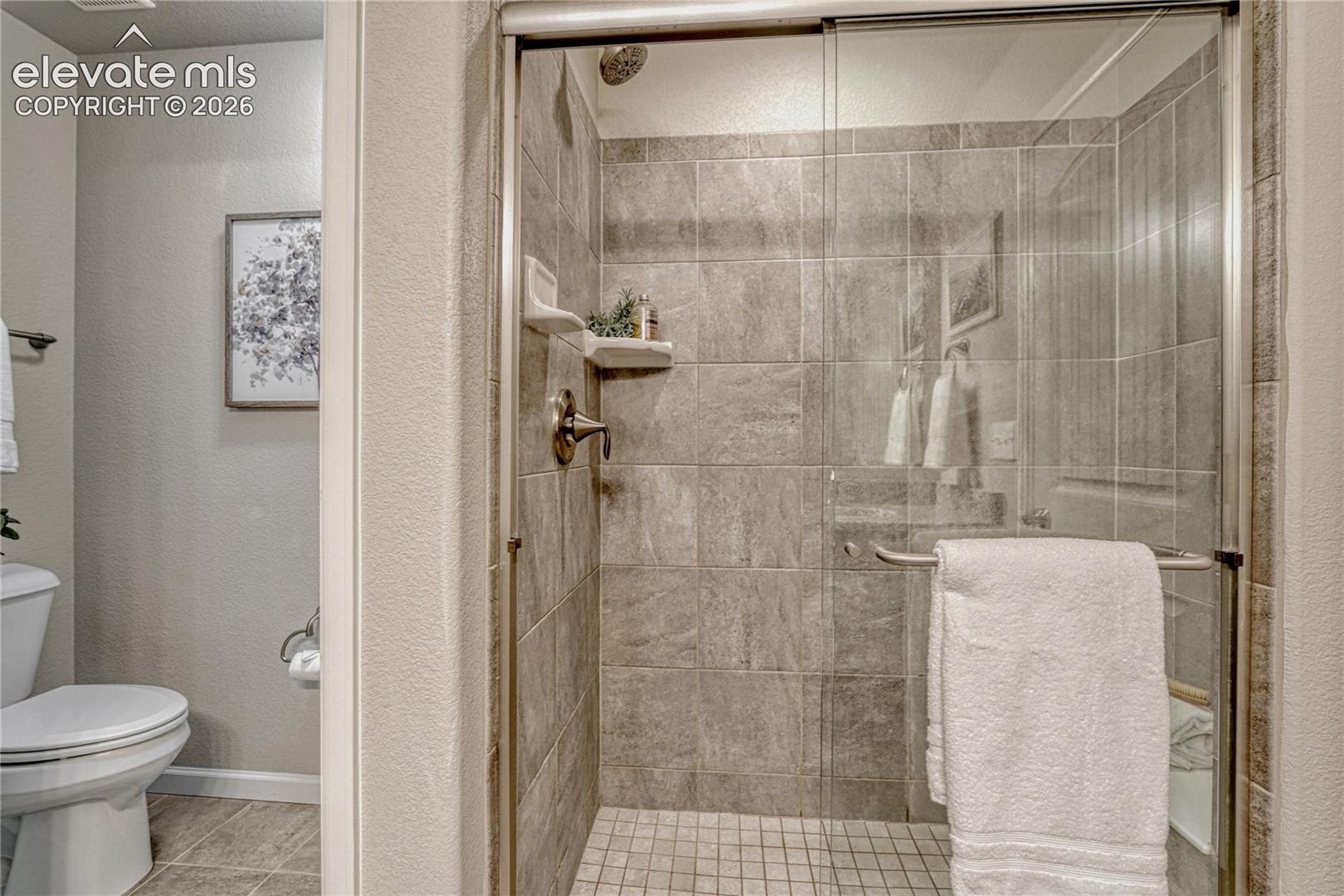 A beautifully finished walk-in shower provides a modern touch with tiled walls and a glass enclosure for a clean, open feel.